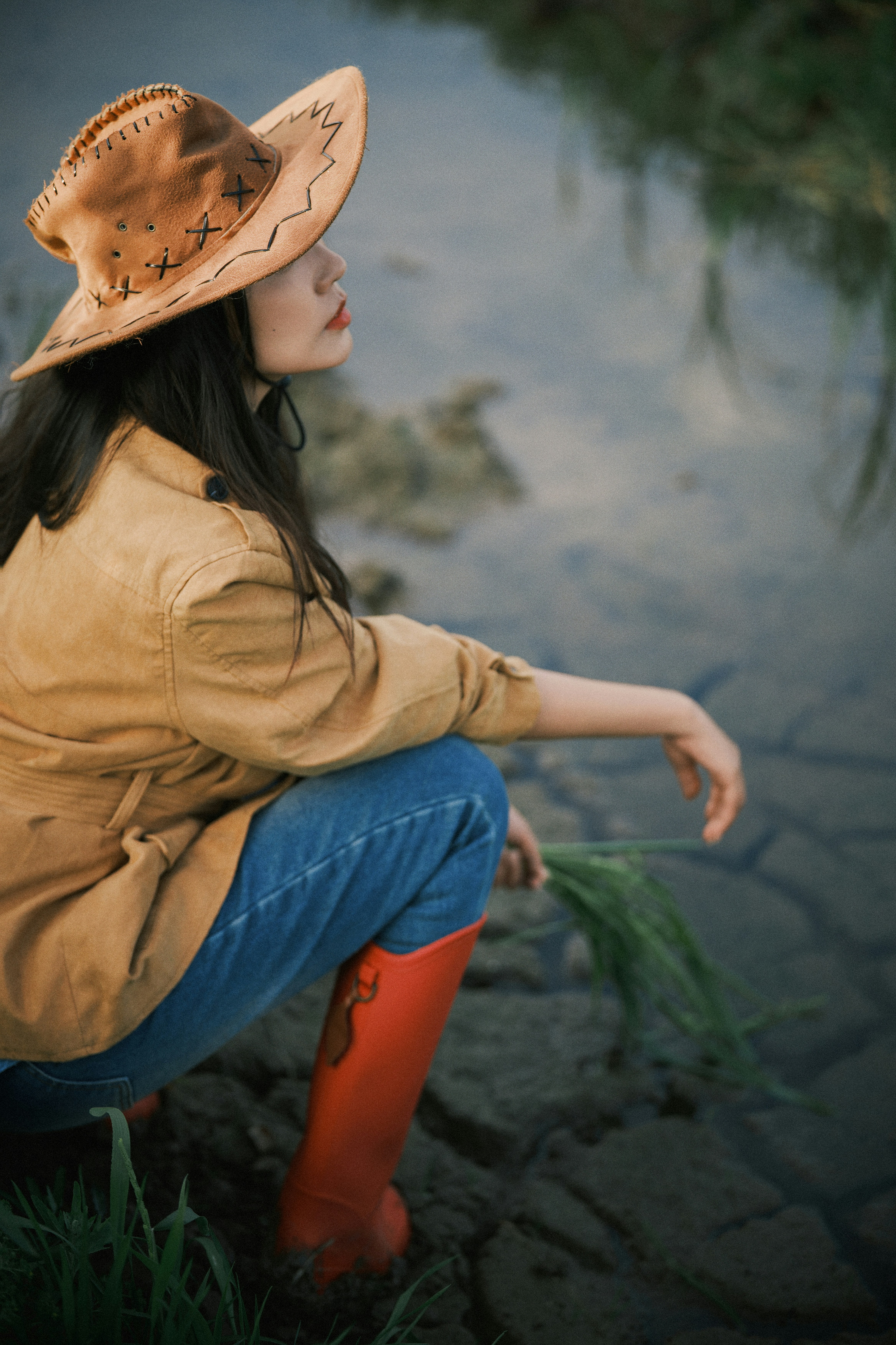 Woman in cowboy hat and boots by water