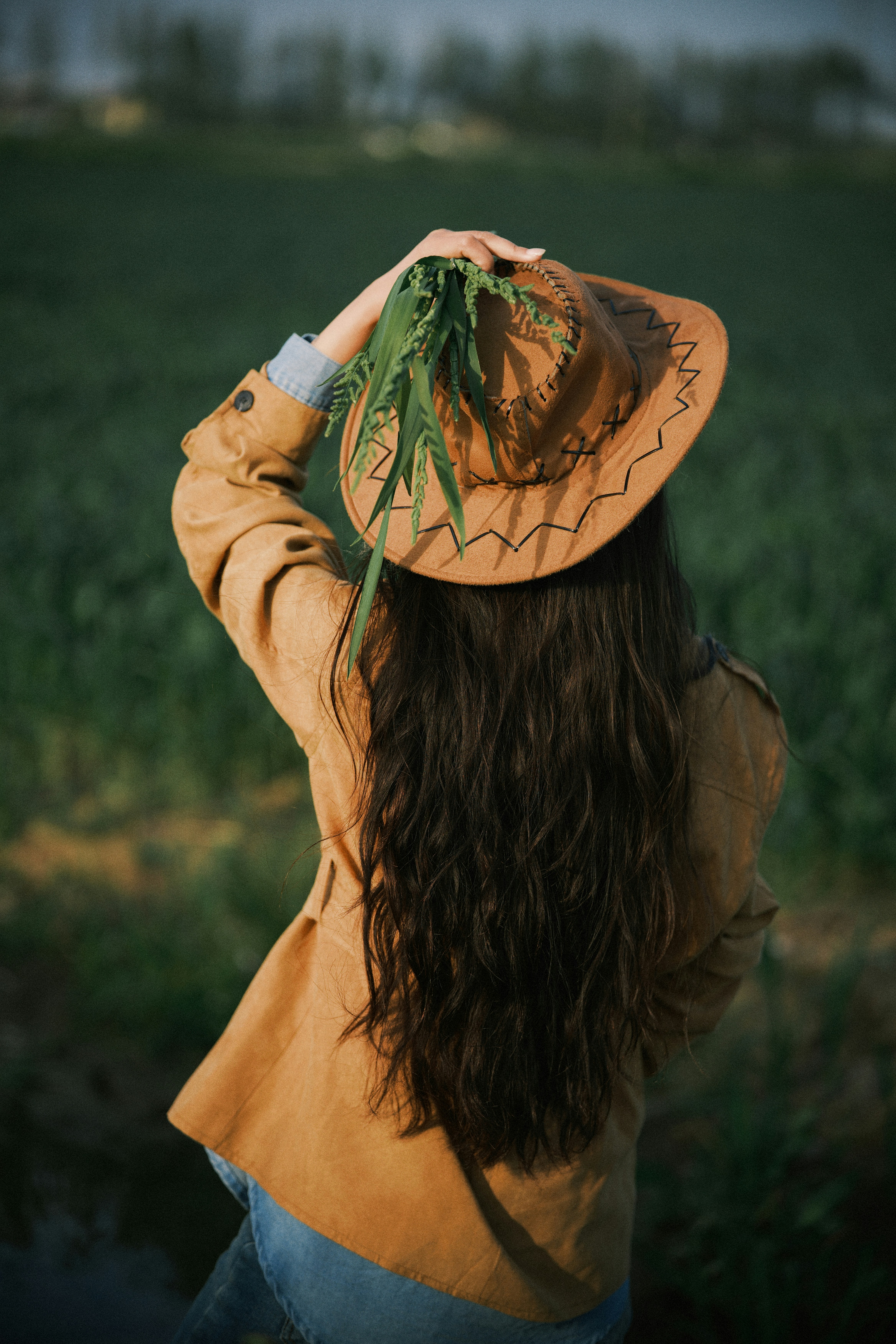Woman in cowboy hat with plant in field