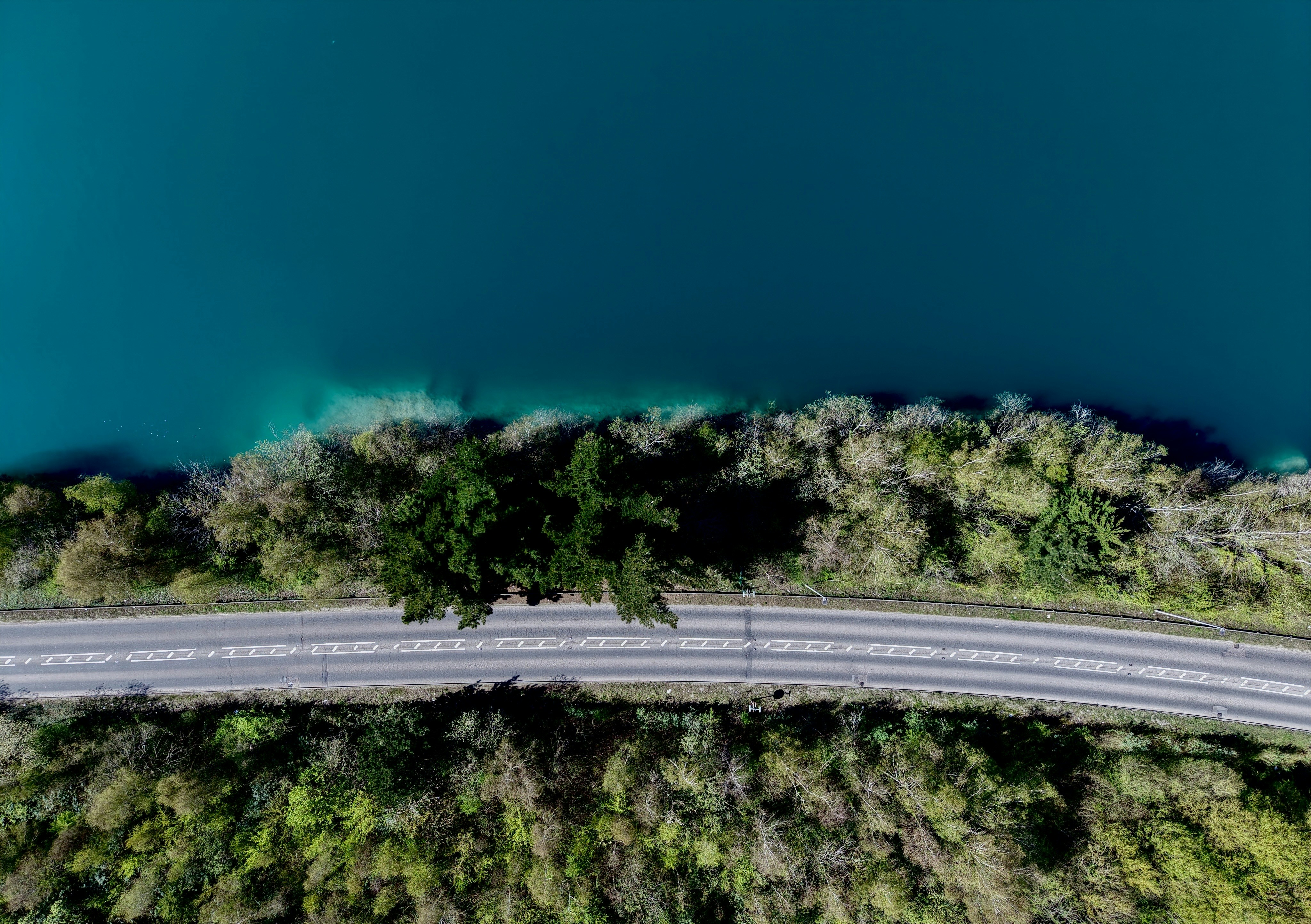 Aerial view of train tracks beside a blue lake.