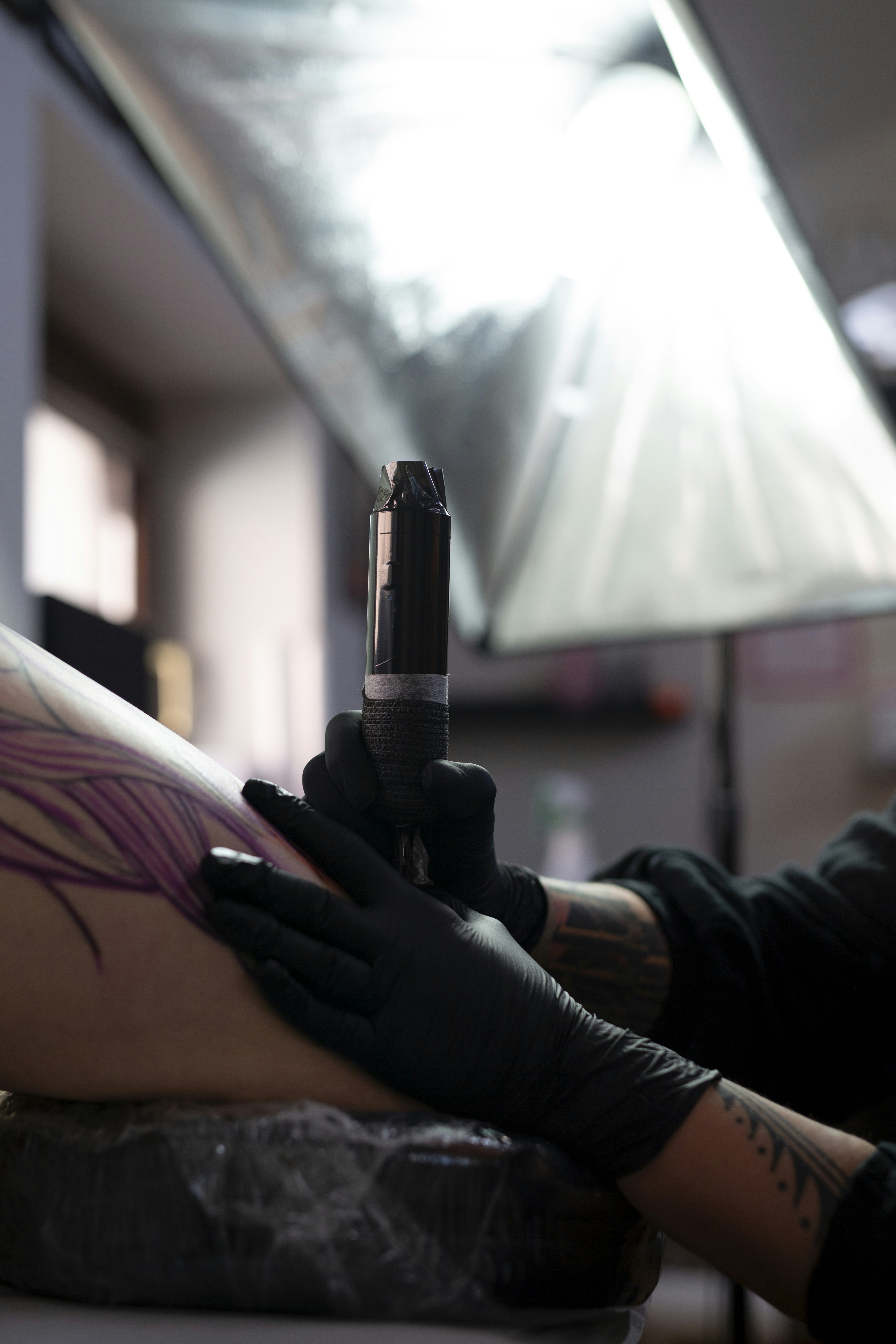 Artist tattooing a feather design on skin