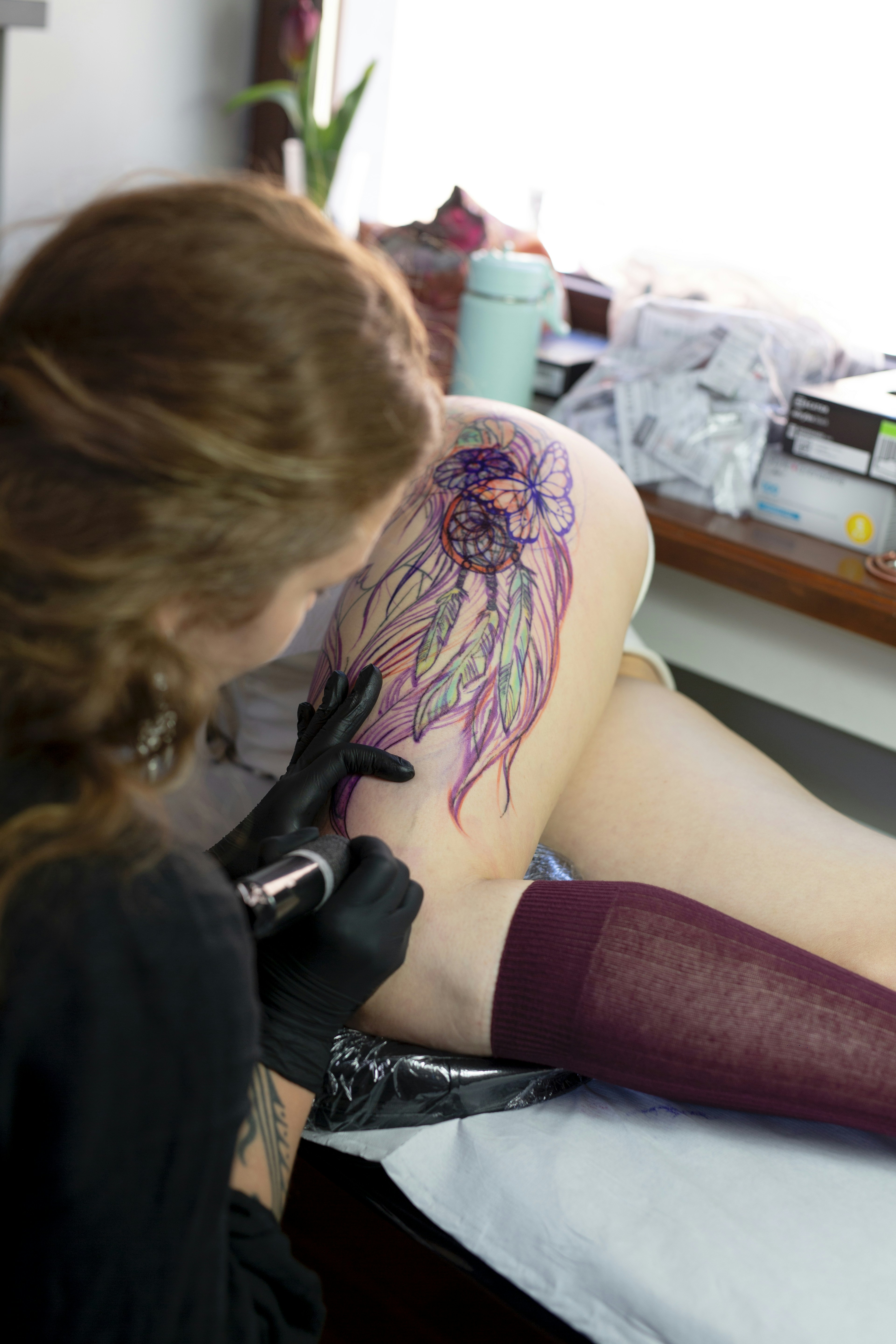 Tattoo artist working on a colorful dreamcatcher tattoo.
