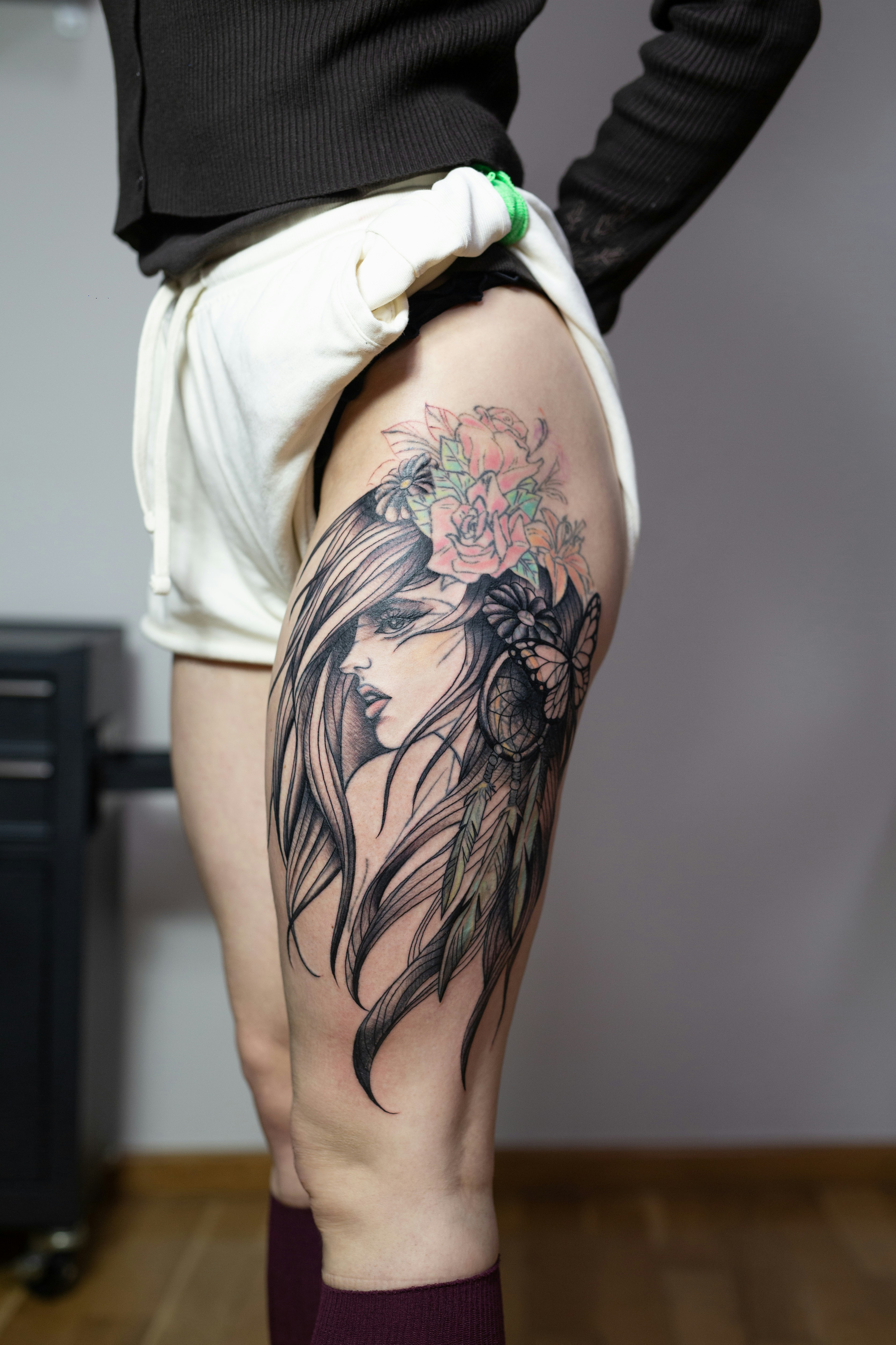 Woman with a detailed thigh tattoo of a woman's face.