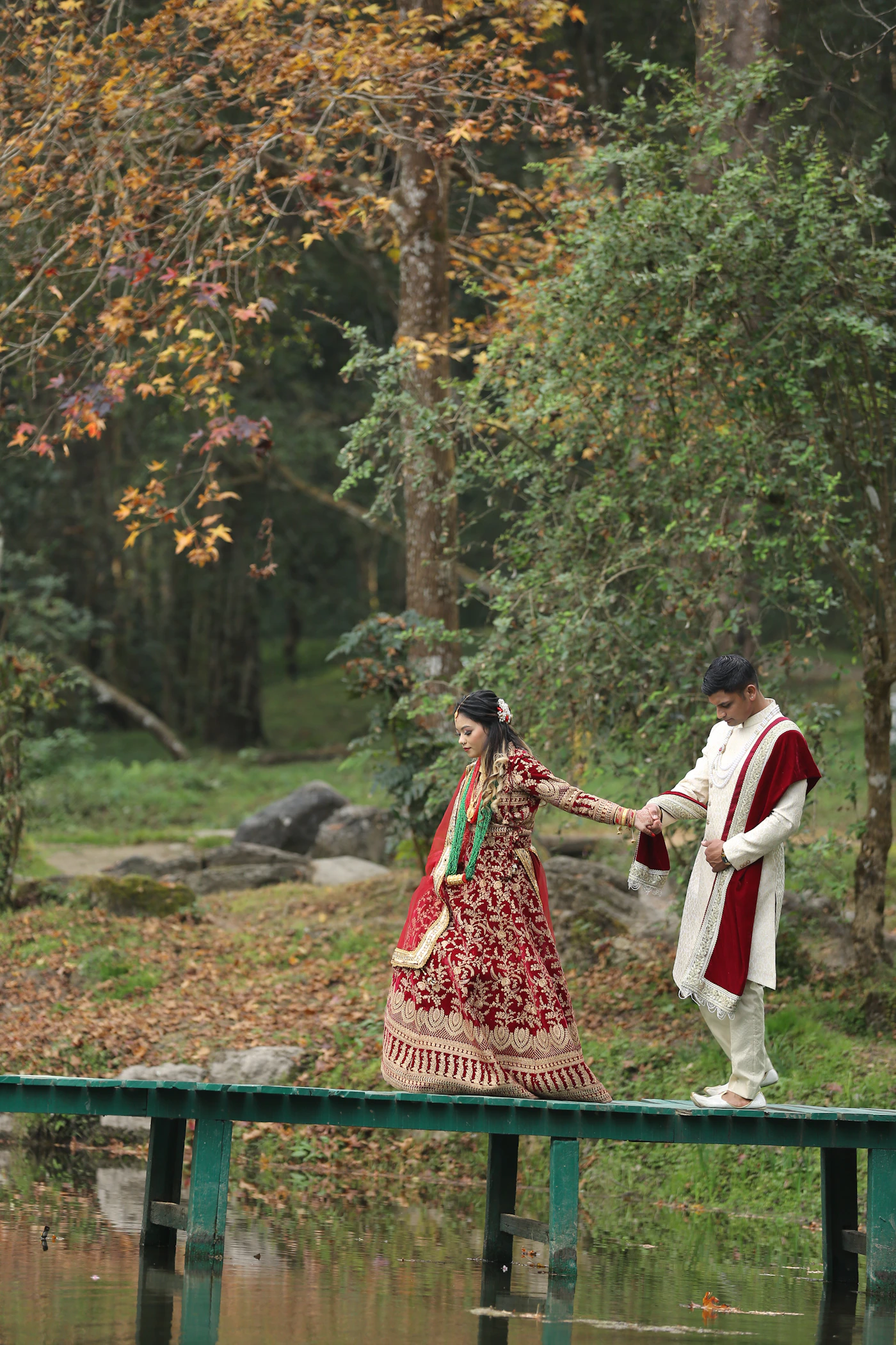 Couple in formal wedding attire walking side by side together across a bridge in soft natural light