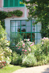 Pink roses bloom by a green-paned window.