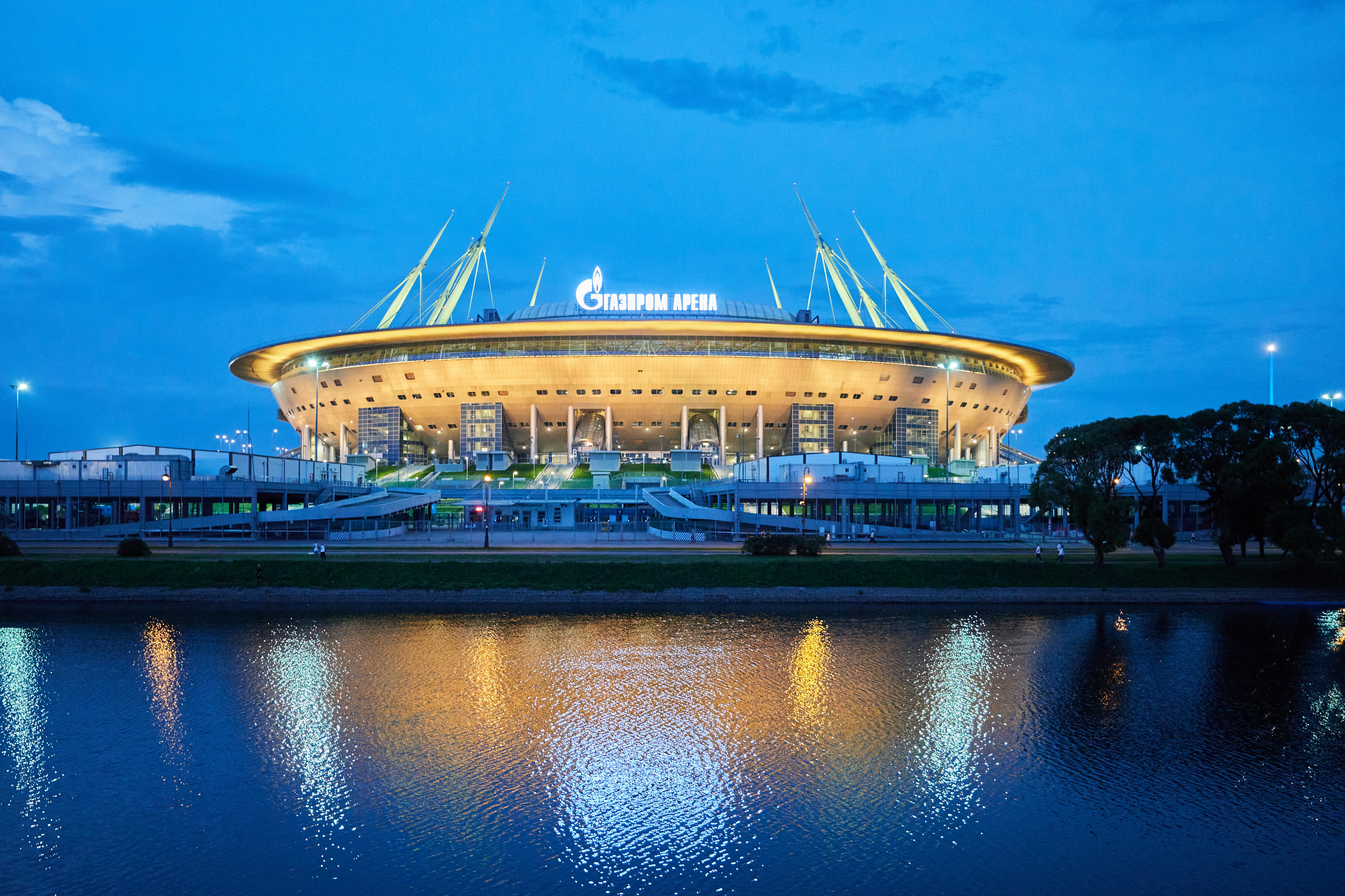 Modern stadium illuminated at dusk with water reflection