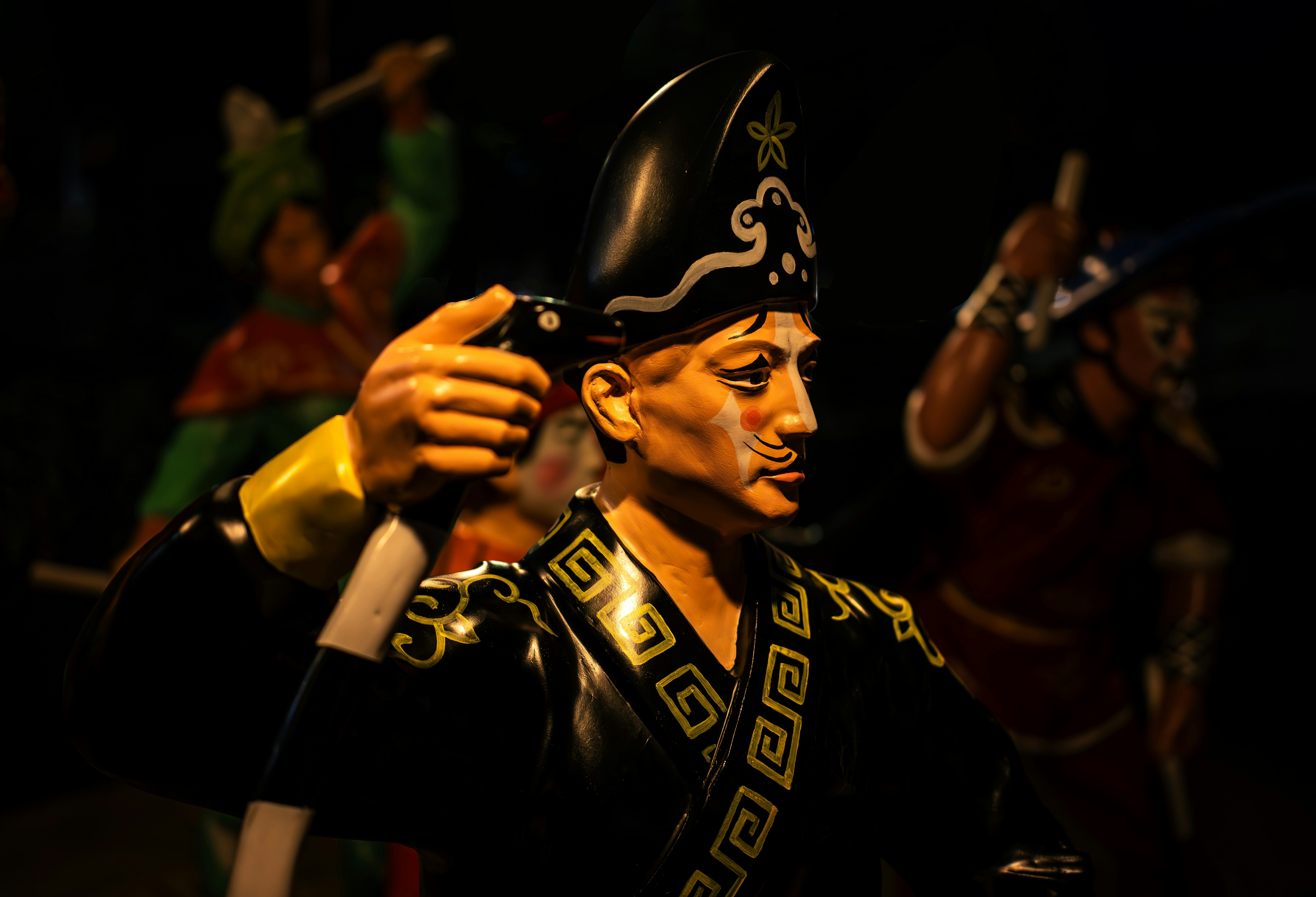 Man in ornate black and gold costume with tall hat
