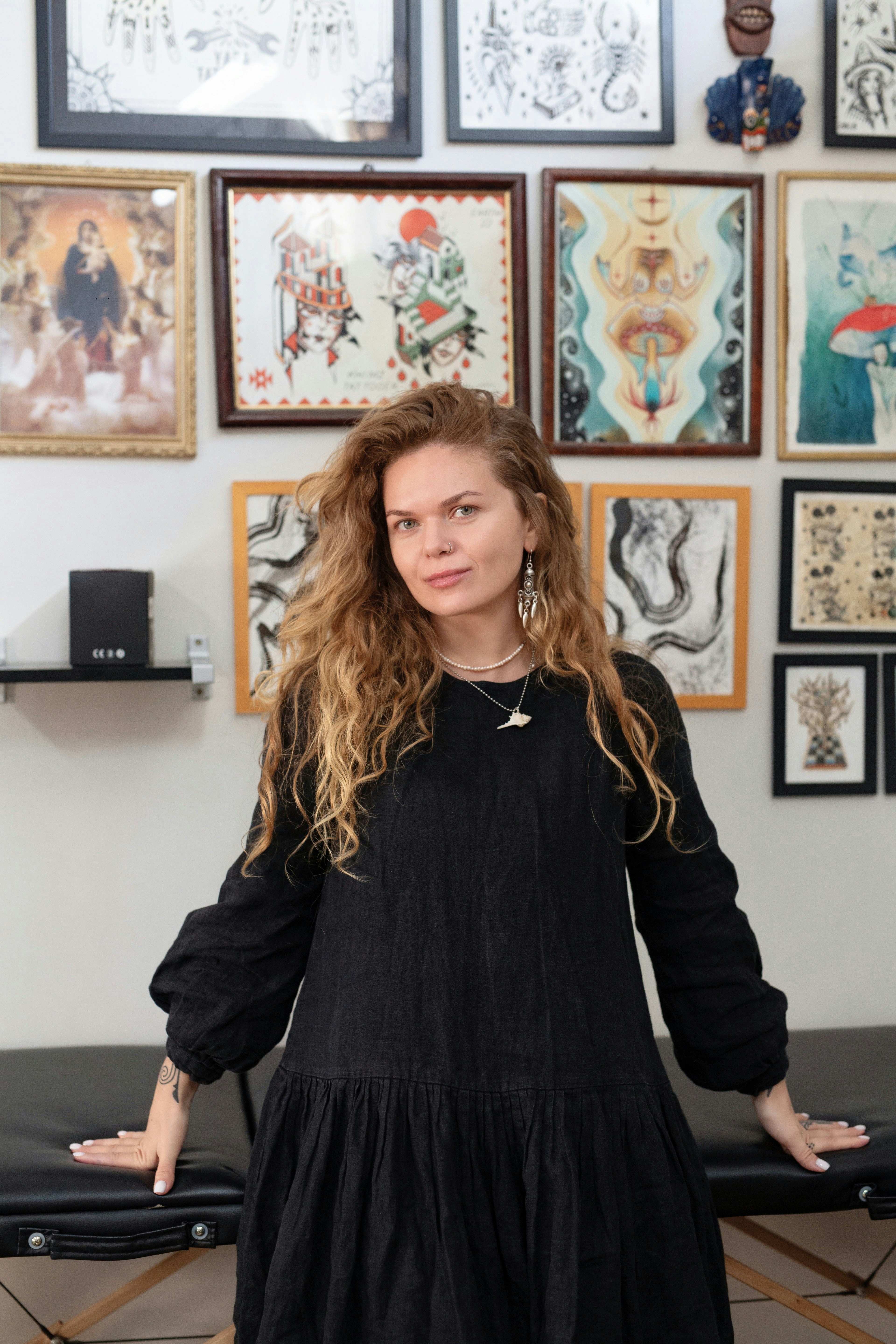 Woman in black dress with curly hair in tattoo studio.