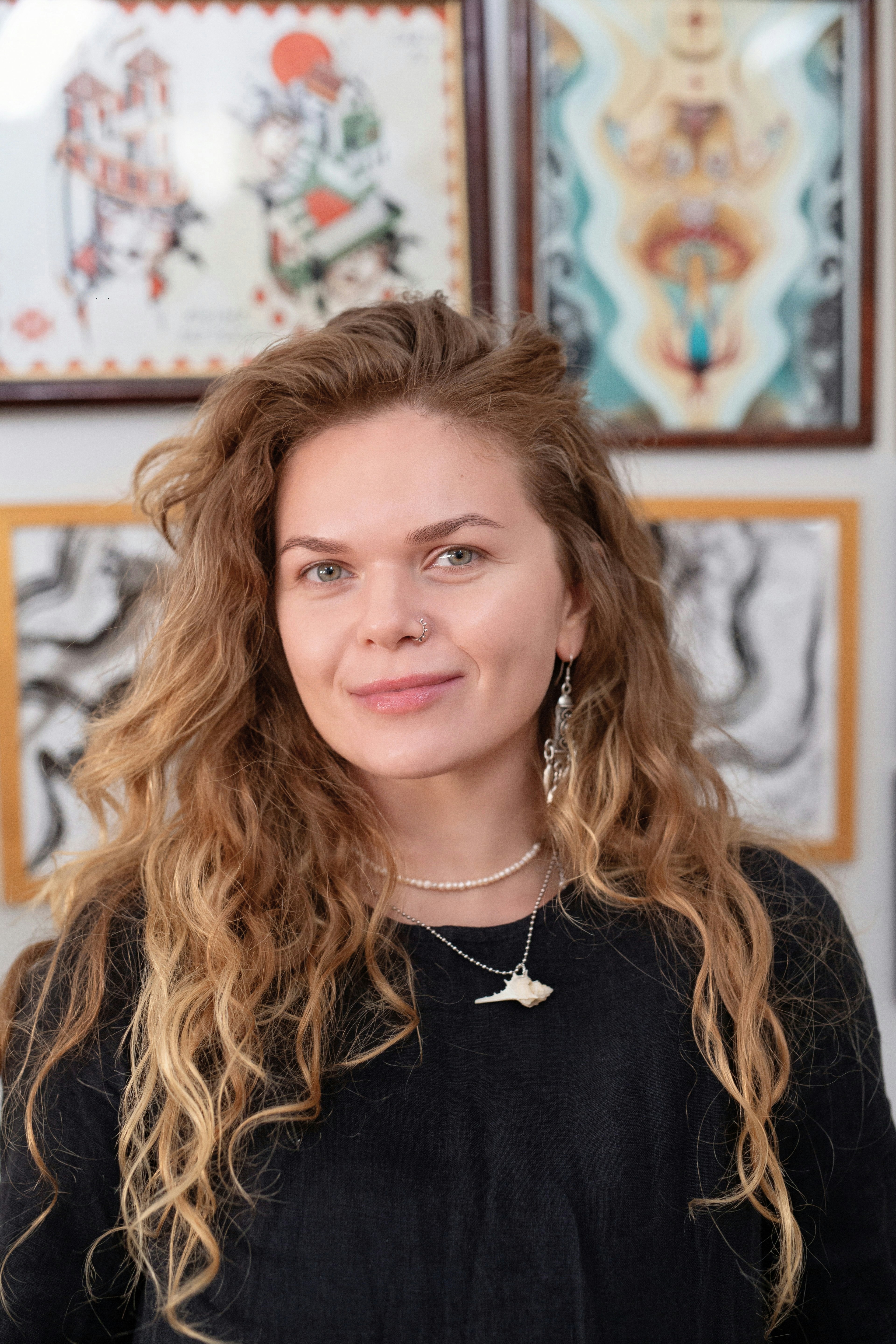 A woman with long curly hair smiles gently.
