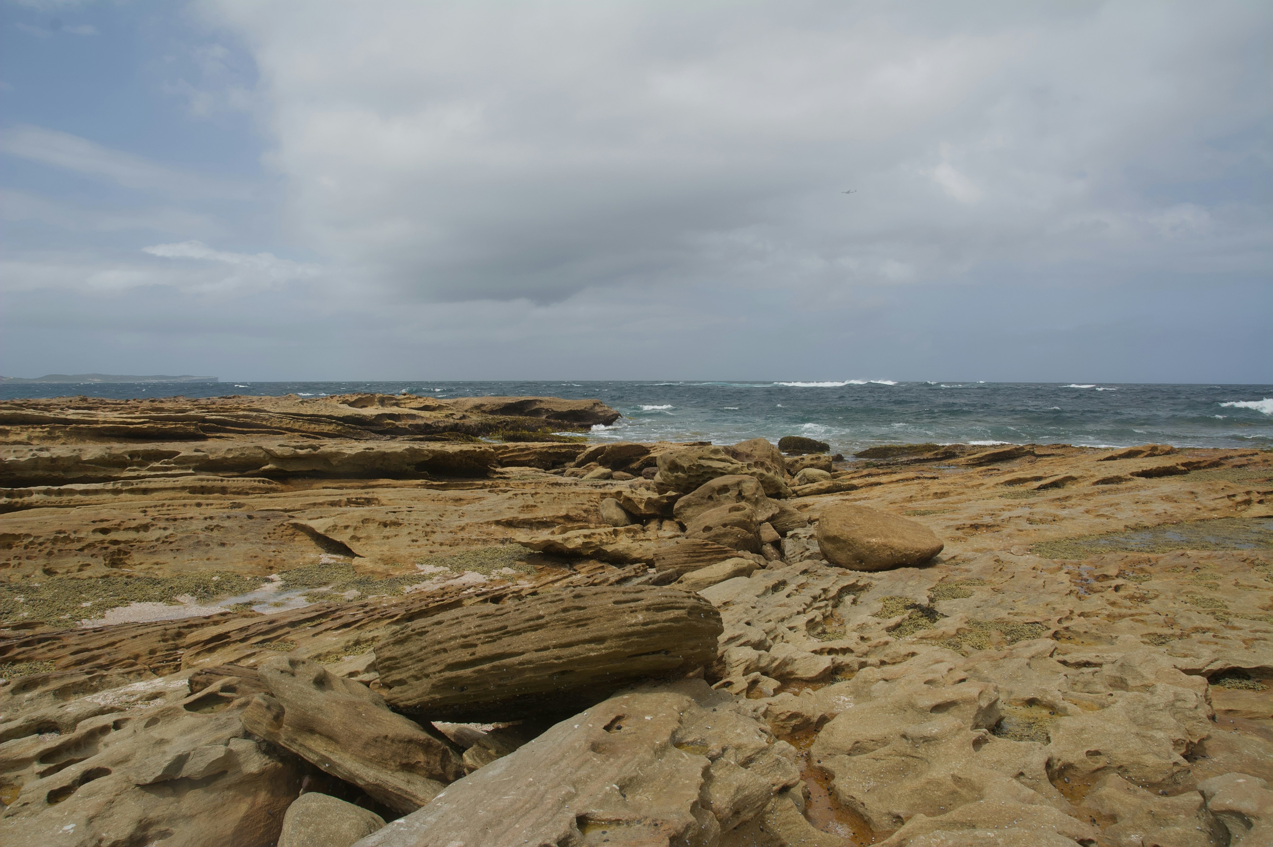 Rocky coastline with waves crashing under cloudy sky