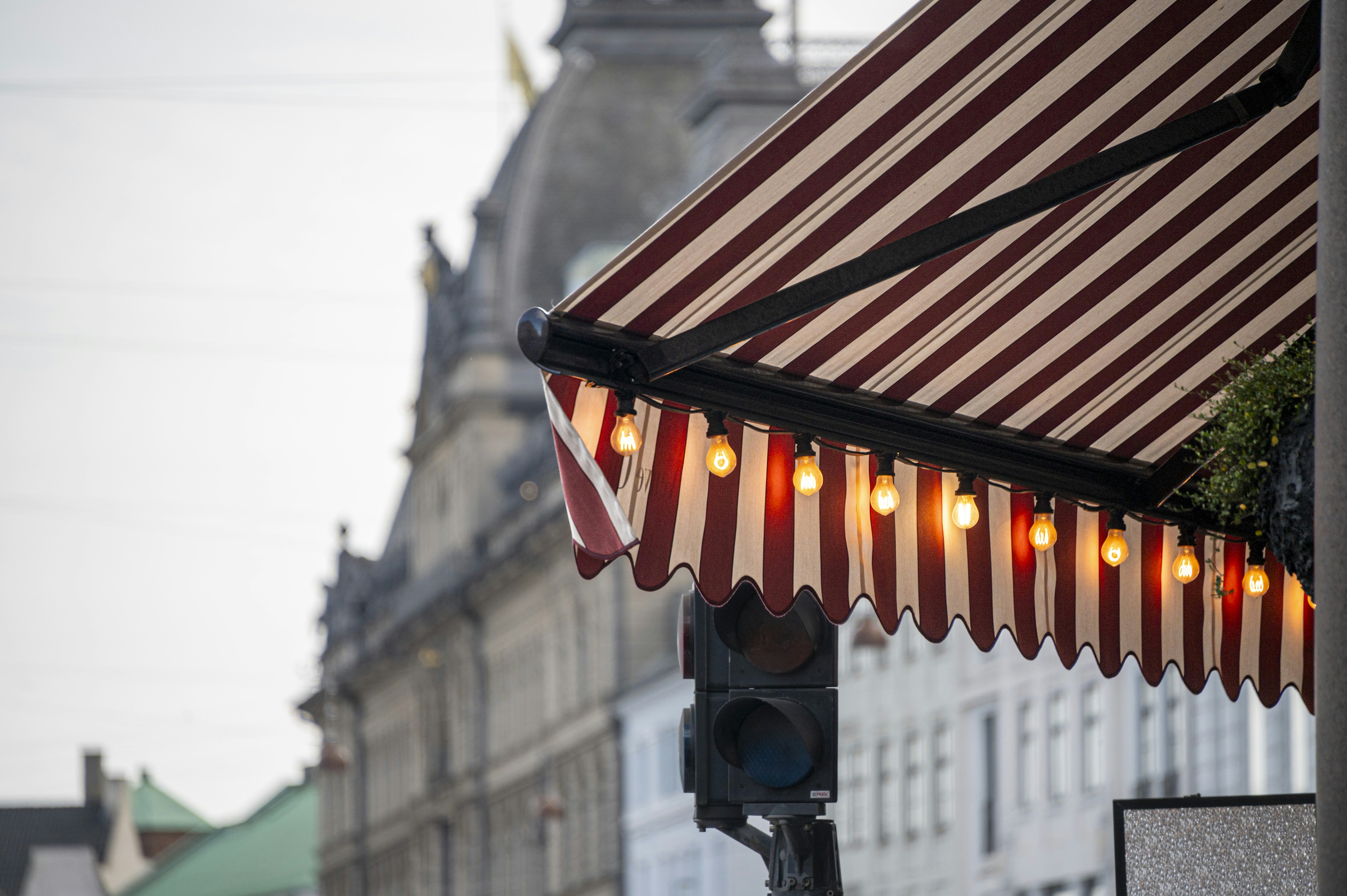 Red and white striped awning with lights above street