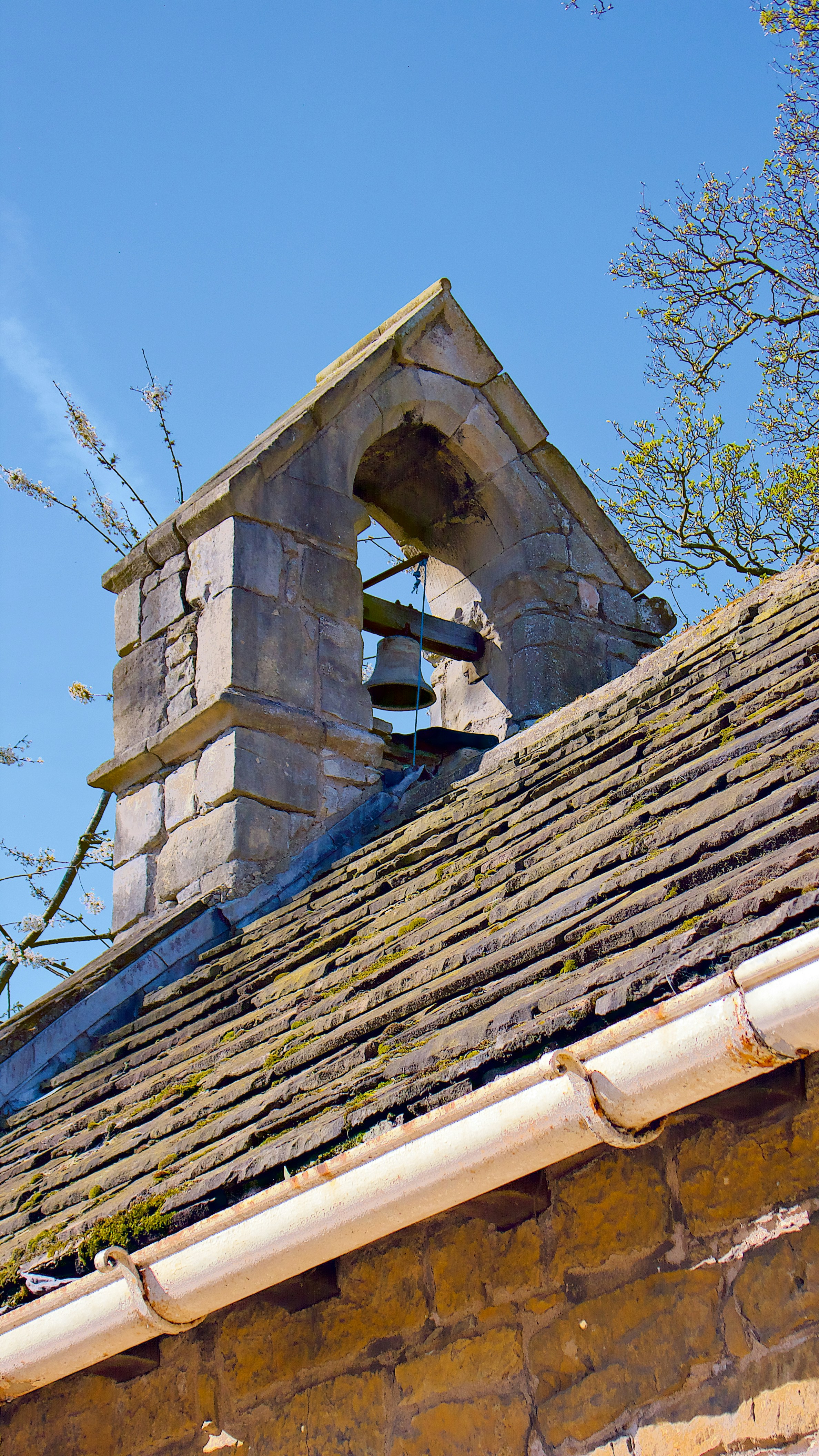 Stone bell tower on a tiled roof under blue sky
