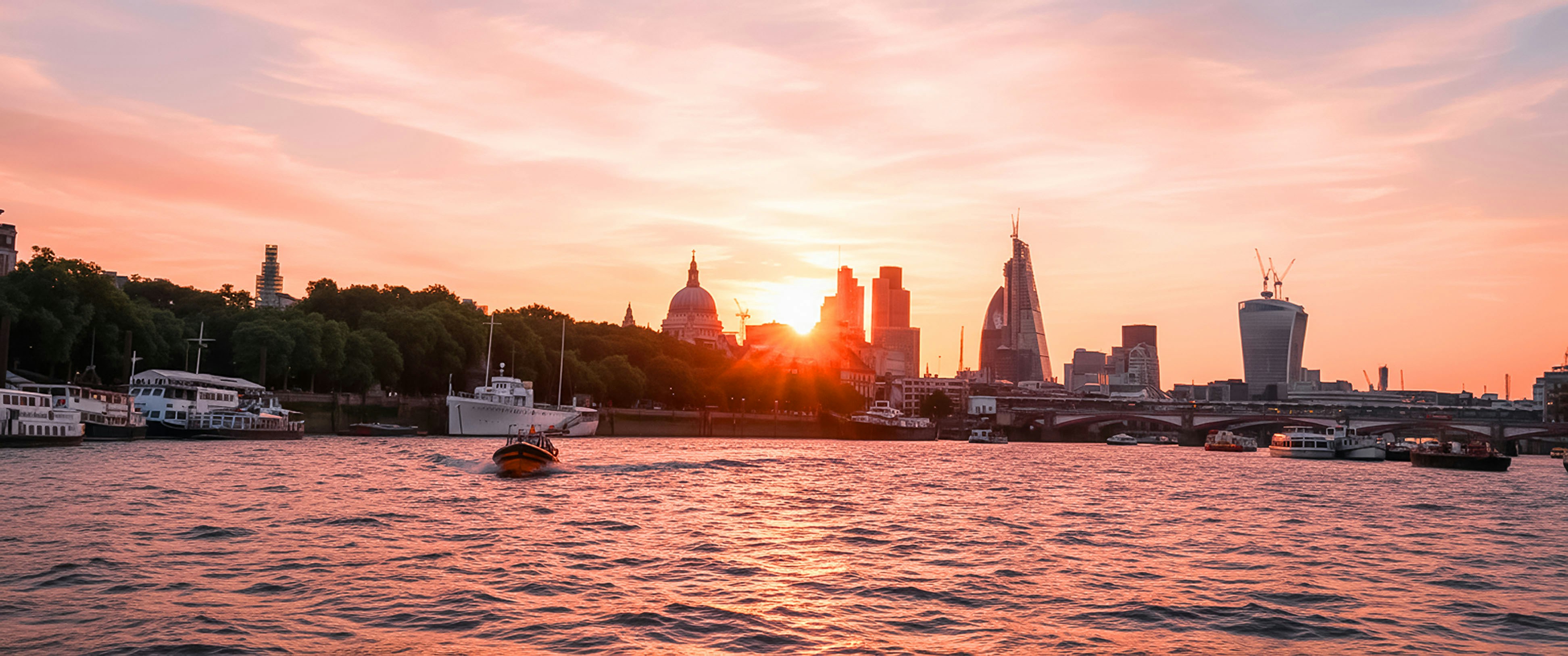 Sunset over a river with a city skyline.