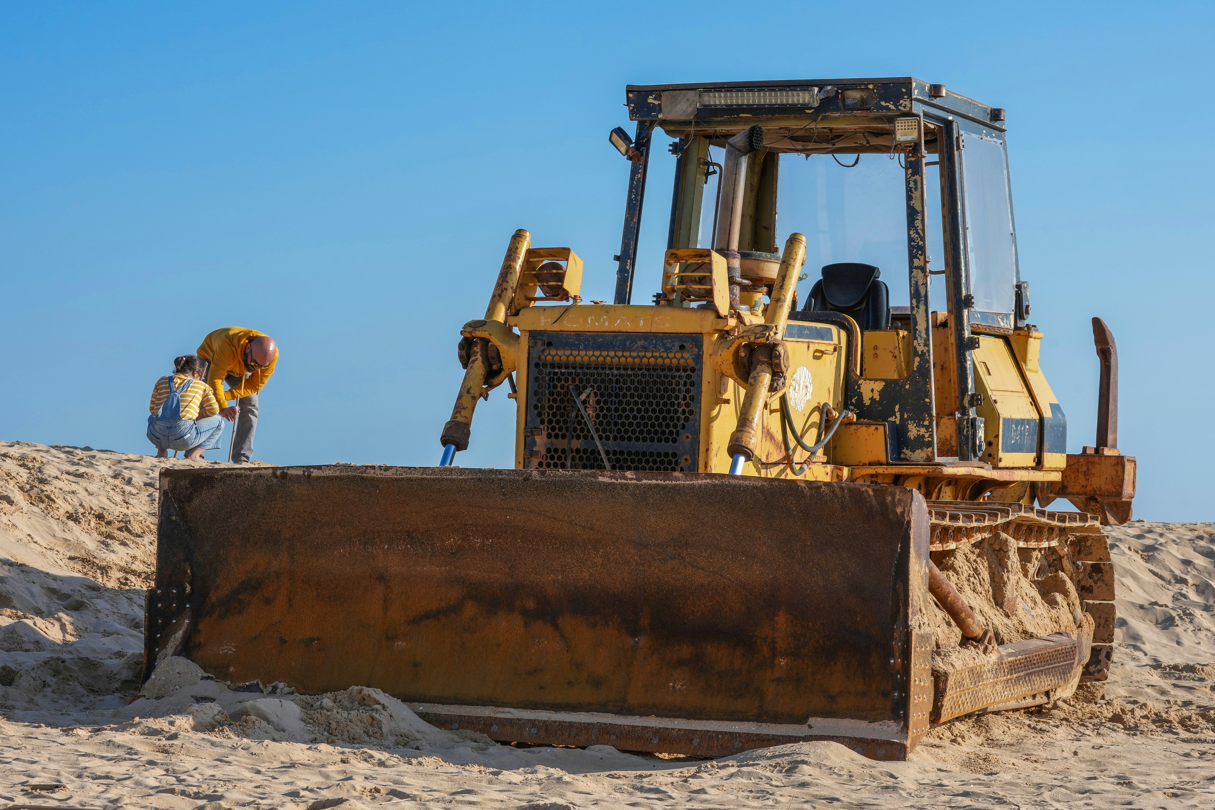Yellow bulldozer on a sandy construction site.