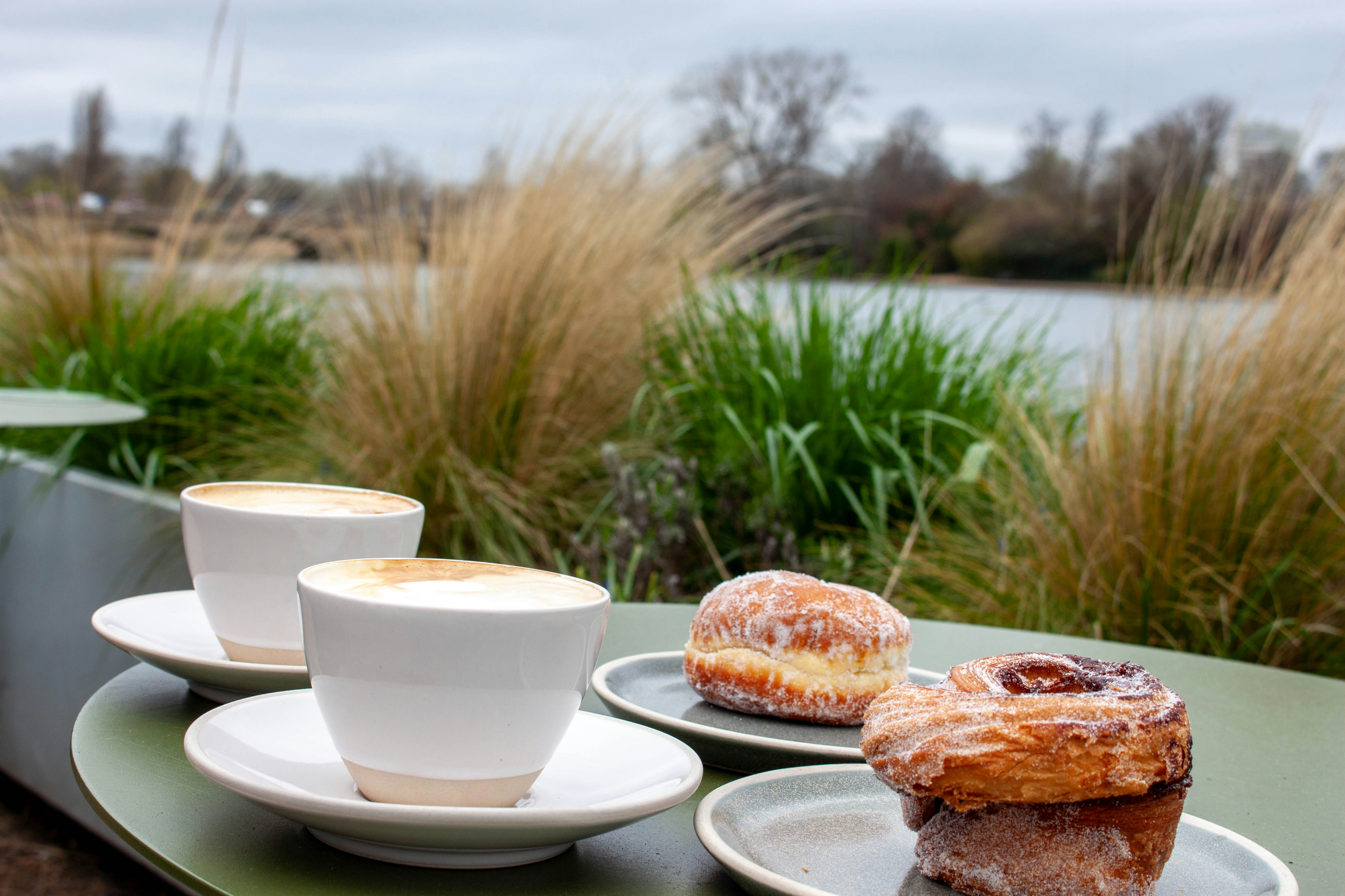 Two coffees and pastries on a table overlooking water