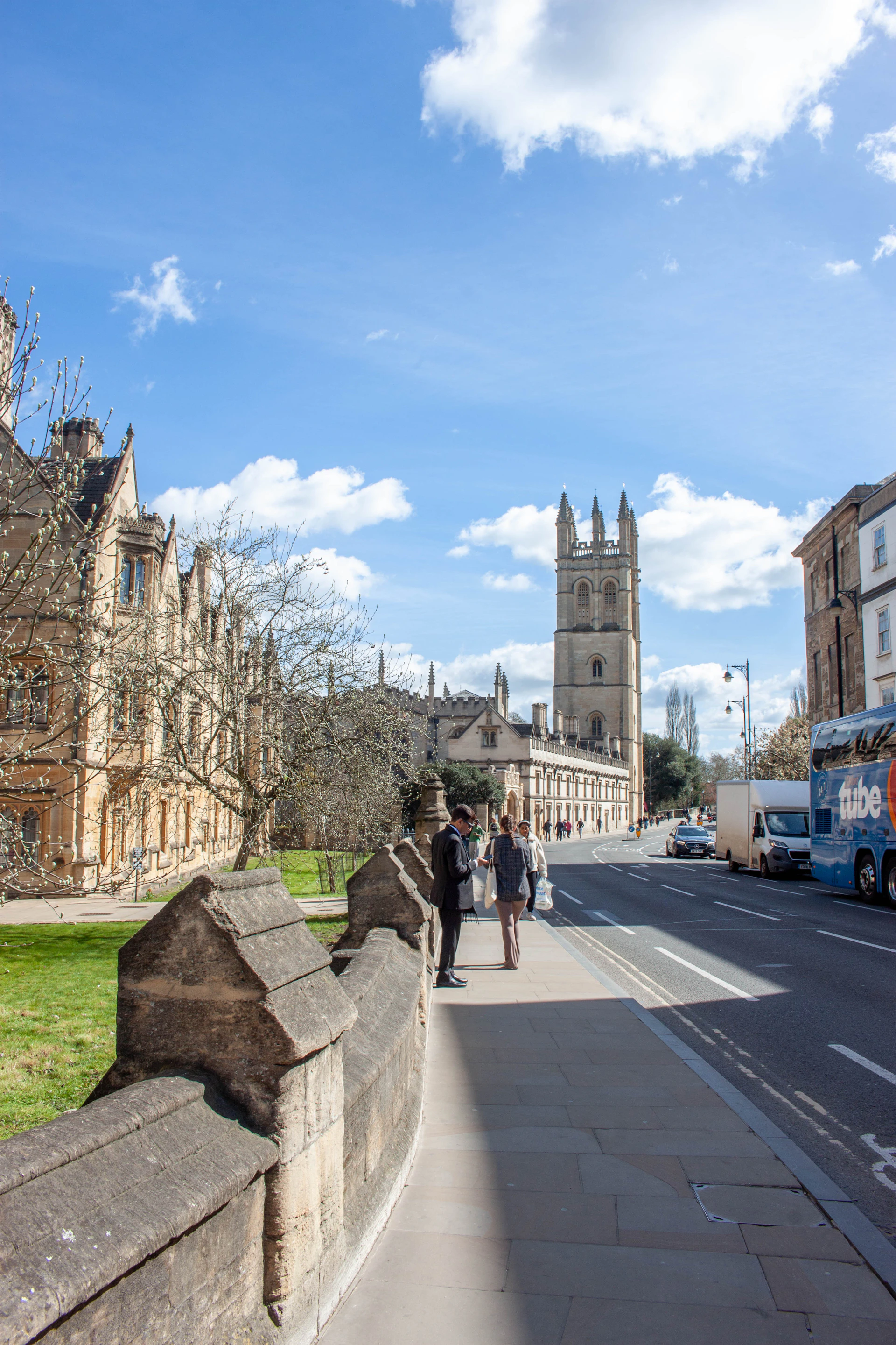 People walk along a street next to historic buildings.