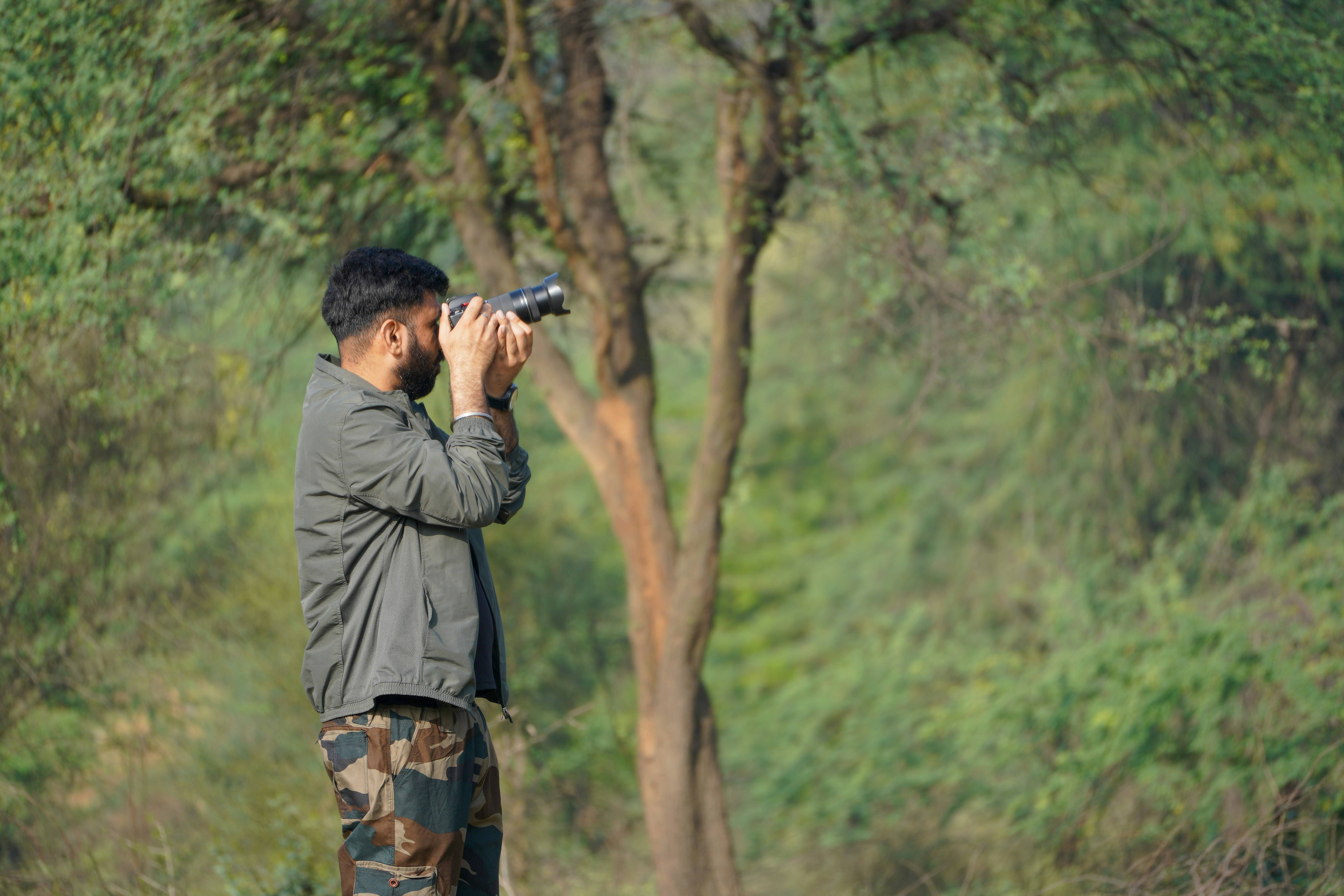 Man with binoculars looking at trees in forest