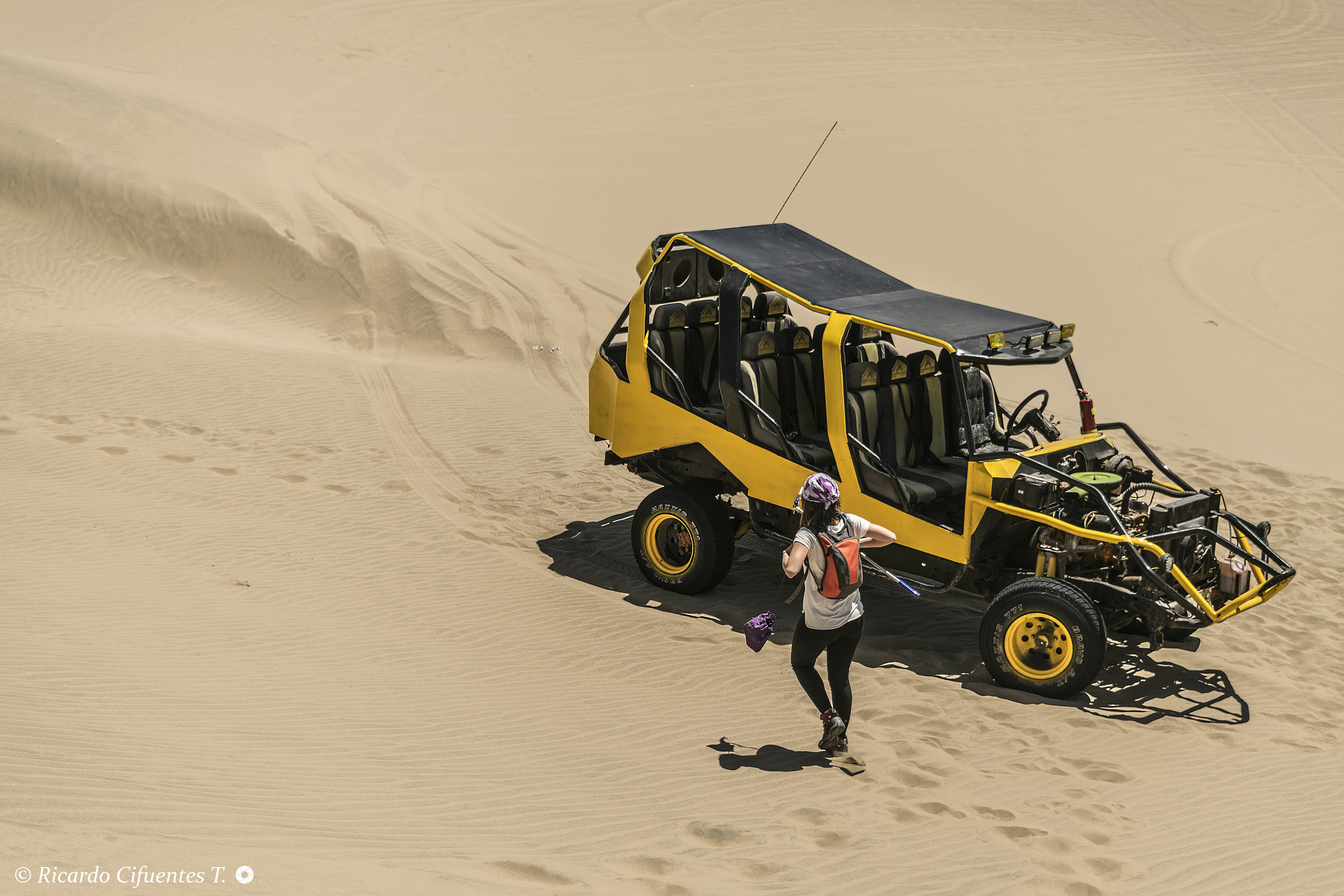A yellow dune buggy parked on a sandy desert landscape
