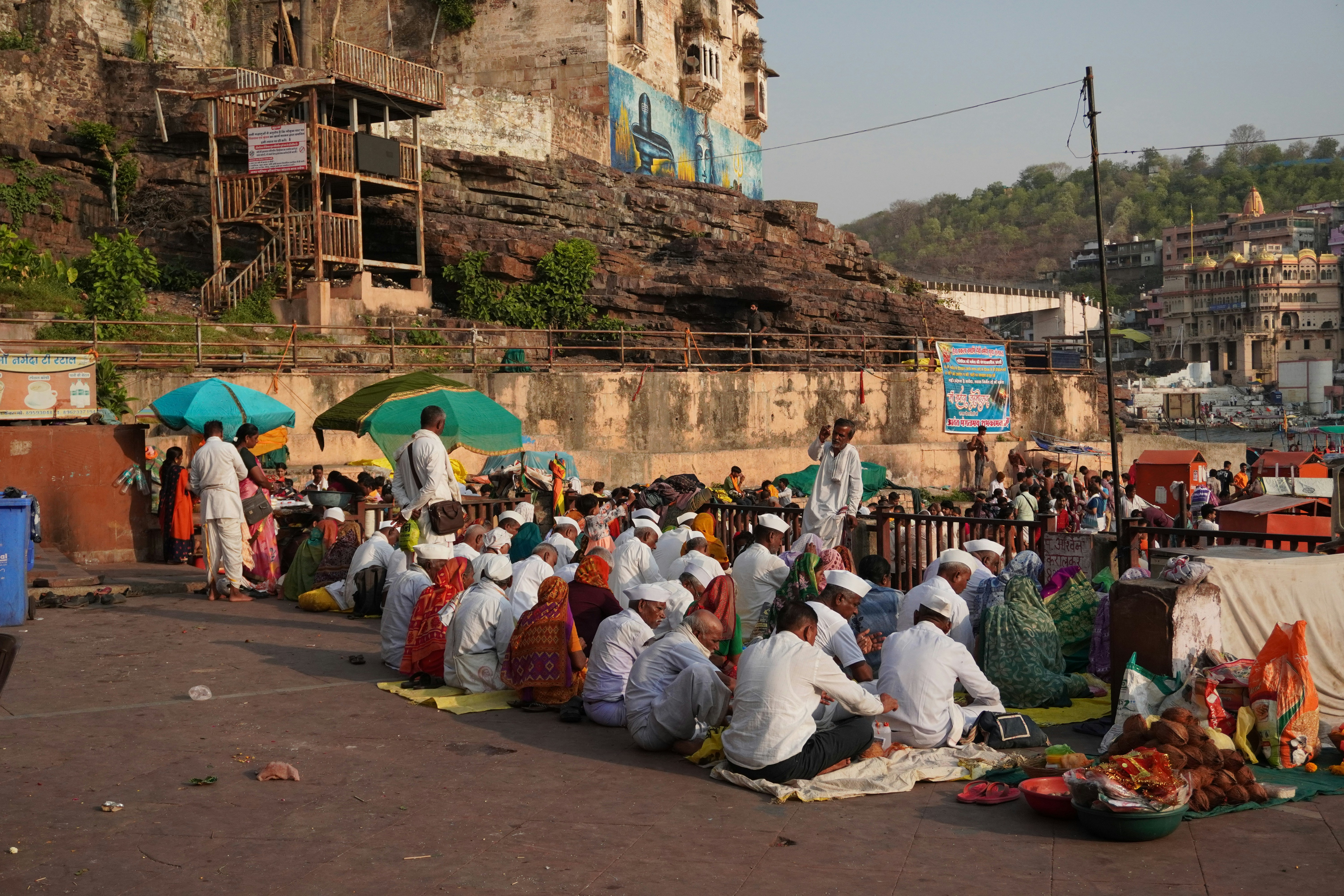 People gathered outdoors near a stone wall and buildings.