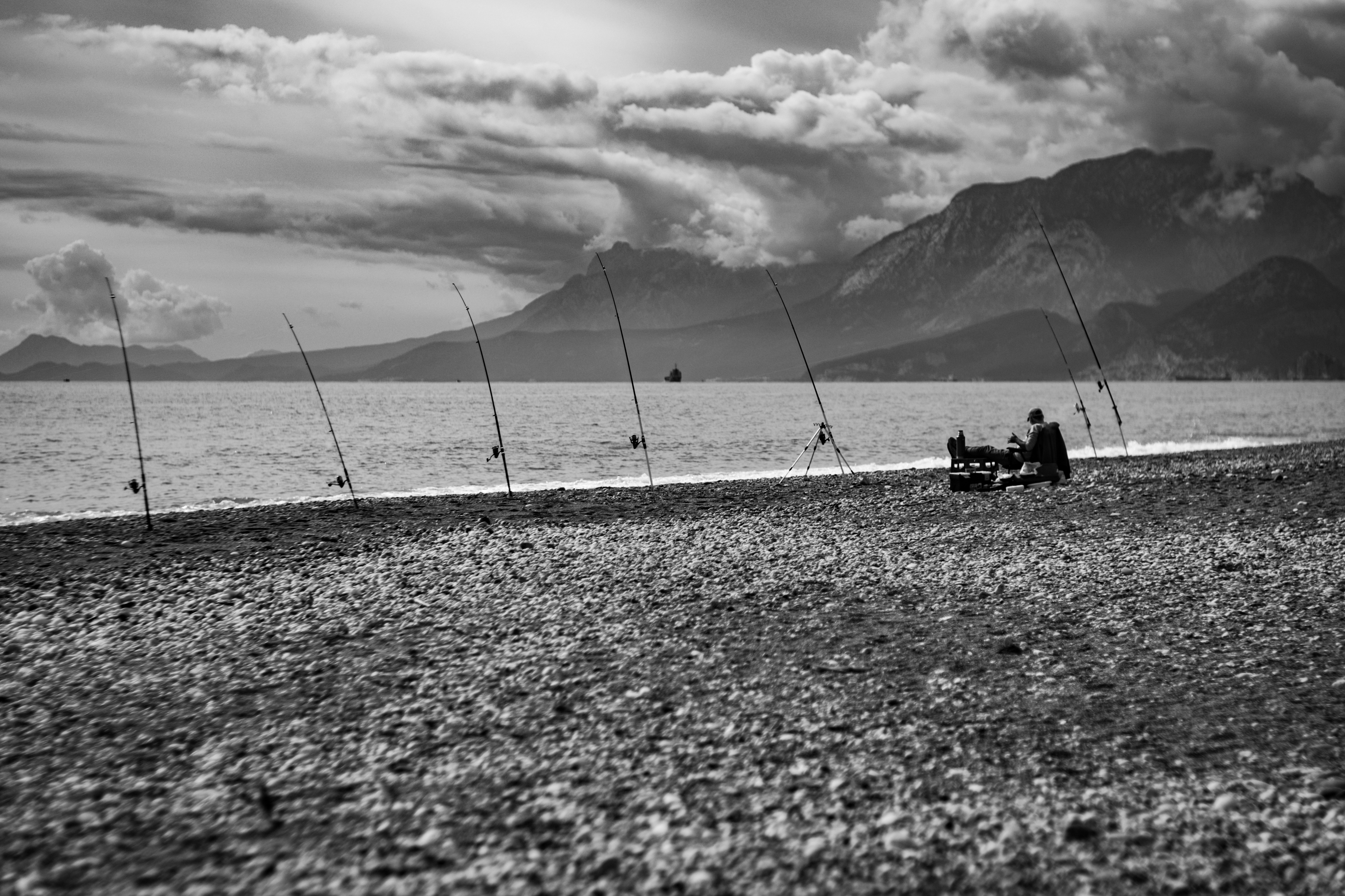 Fisherman sitting by the sea with many fishing rods.