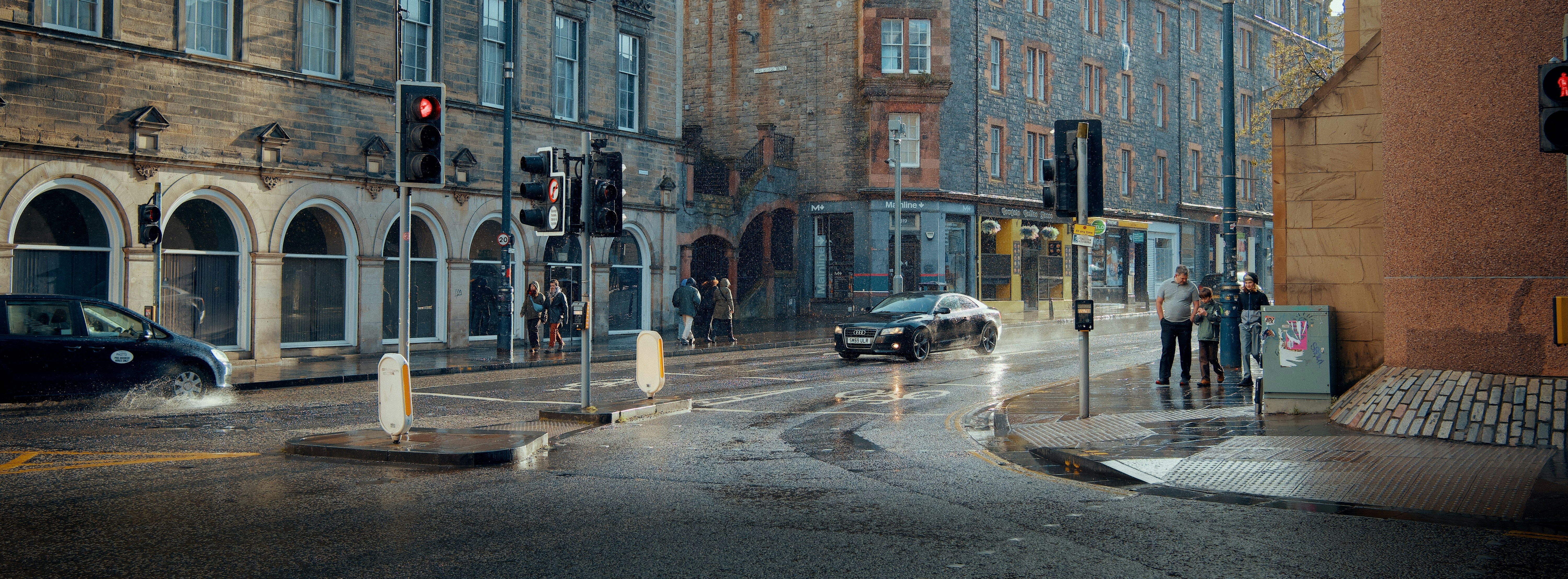 Cars drive through a wet city street at night.