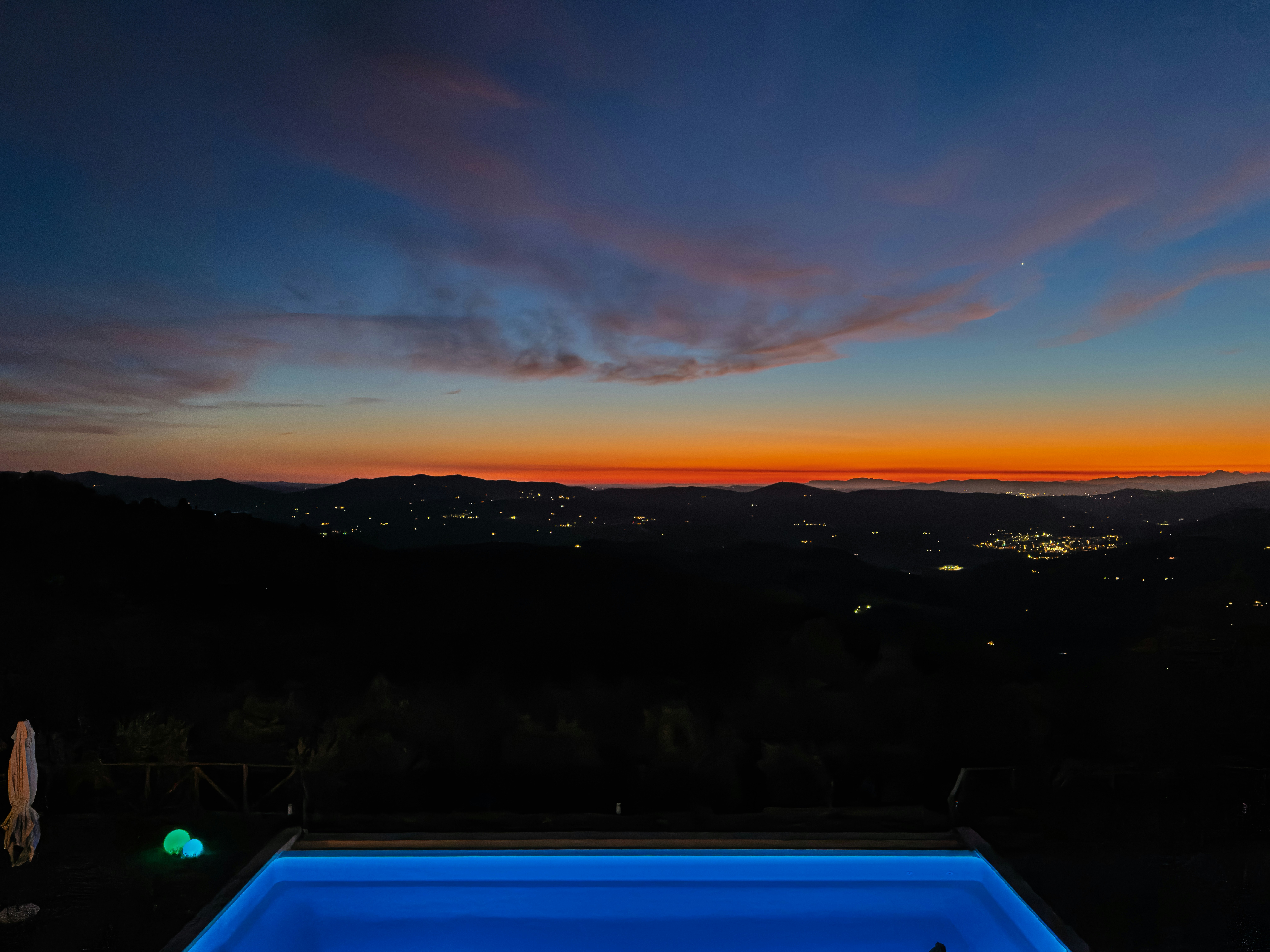 Vibrant sunset over a distant town with a pool.