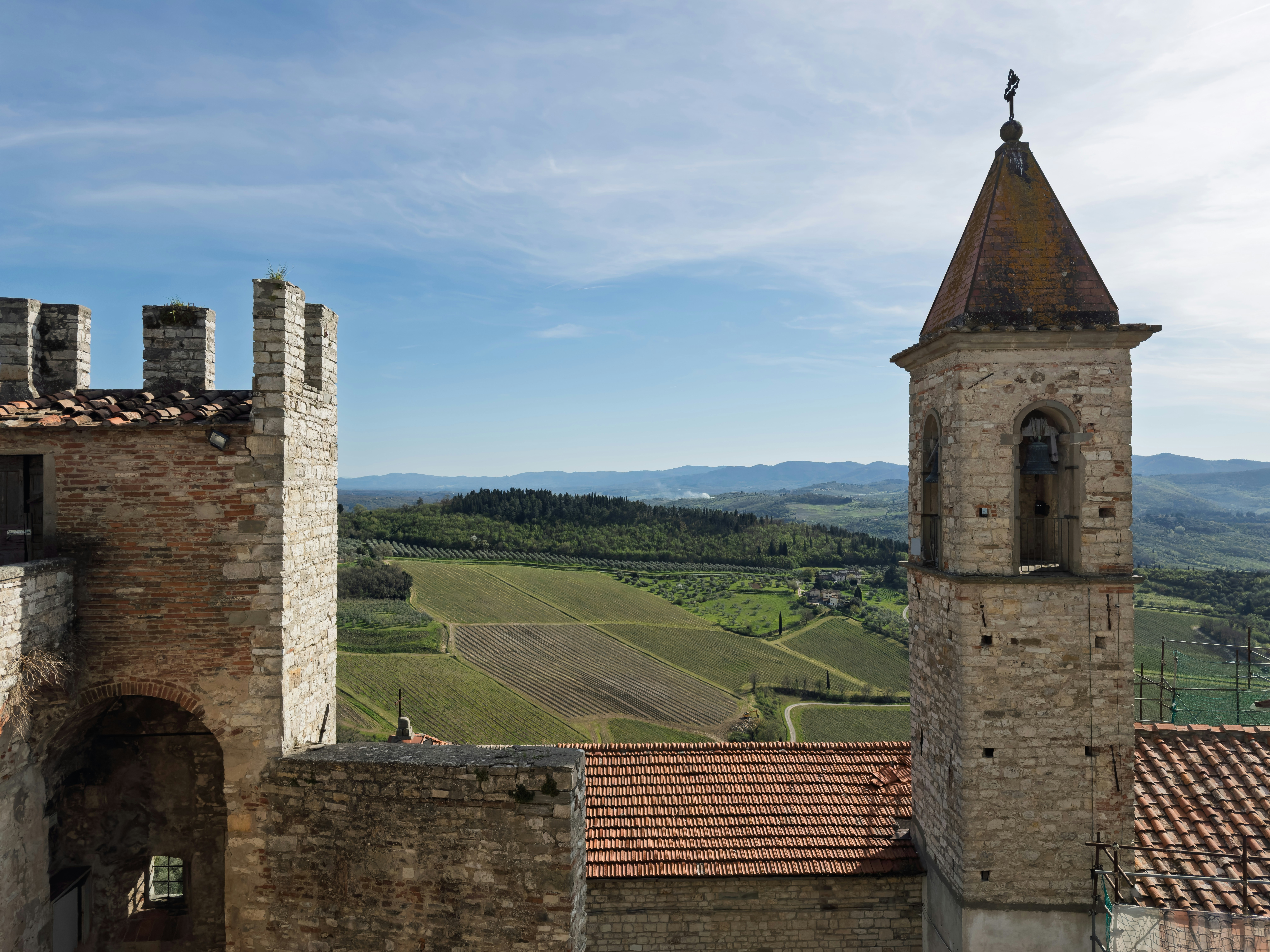 Stone tower and castle wall overlook rolling green hills.