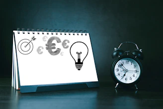 Desk calendar with business symbols and alarm clock.