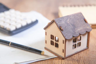 Model house with calculator and pen on desk.