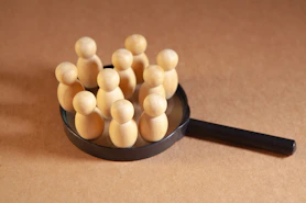 Wooden figures clustered on a magnifying glass