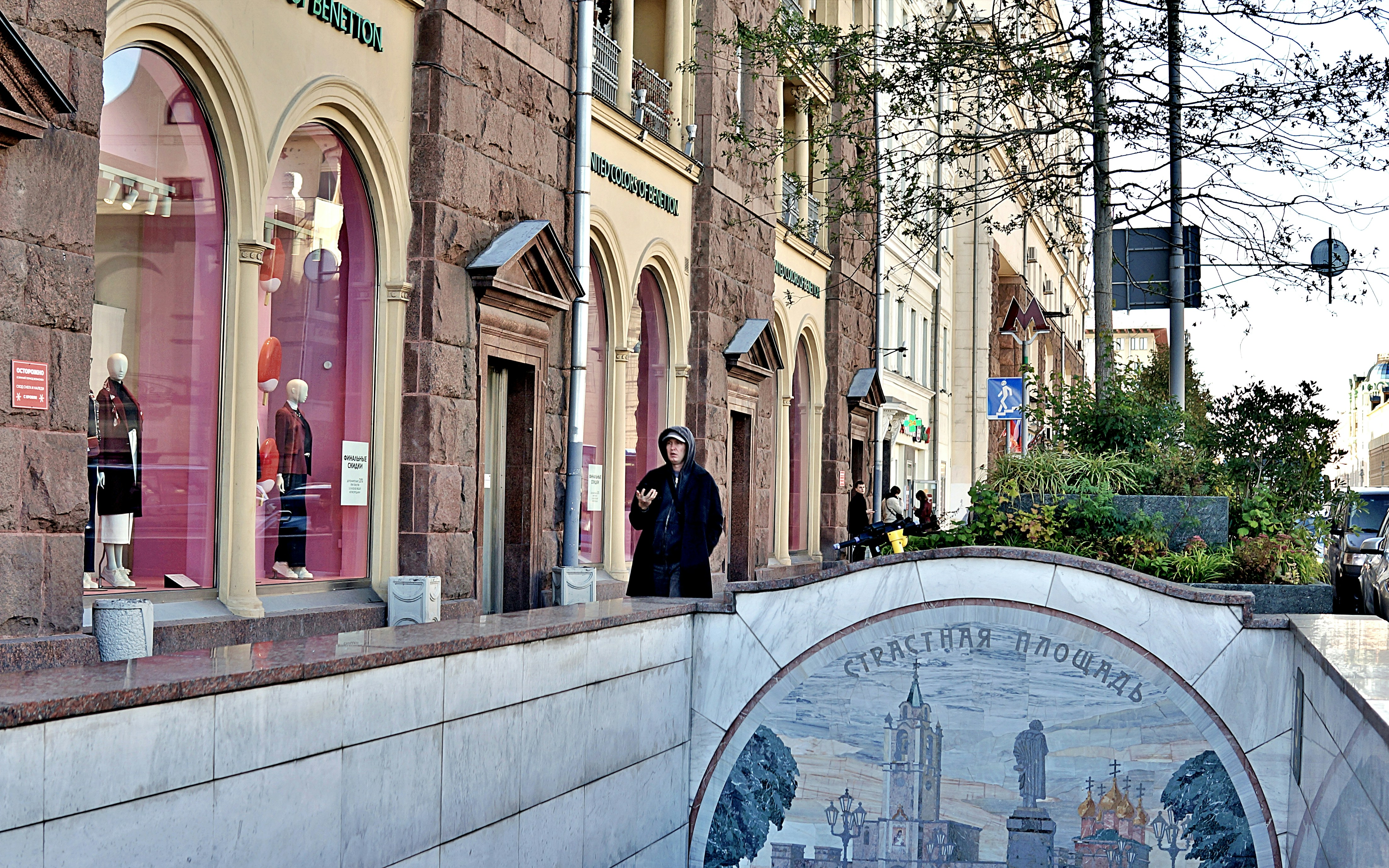 Un homme debout dans une rue avec des bâtiments et des boutiques.