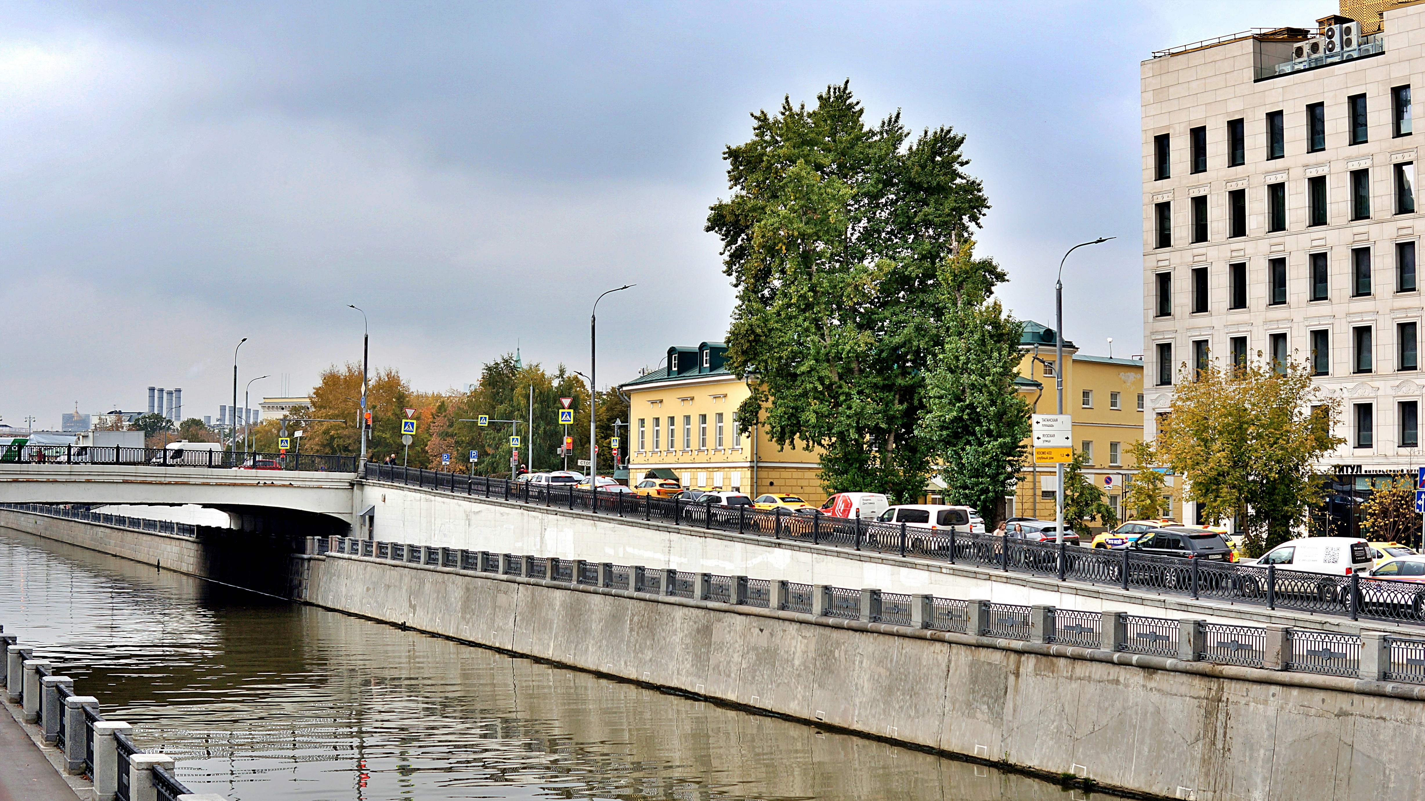 Canal urbain avec voitures et bâtiments sous un ciel nuageux