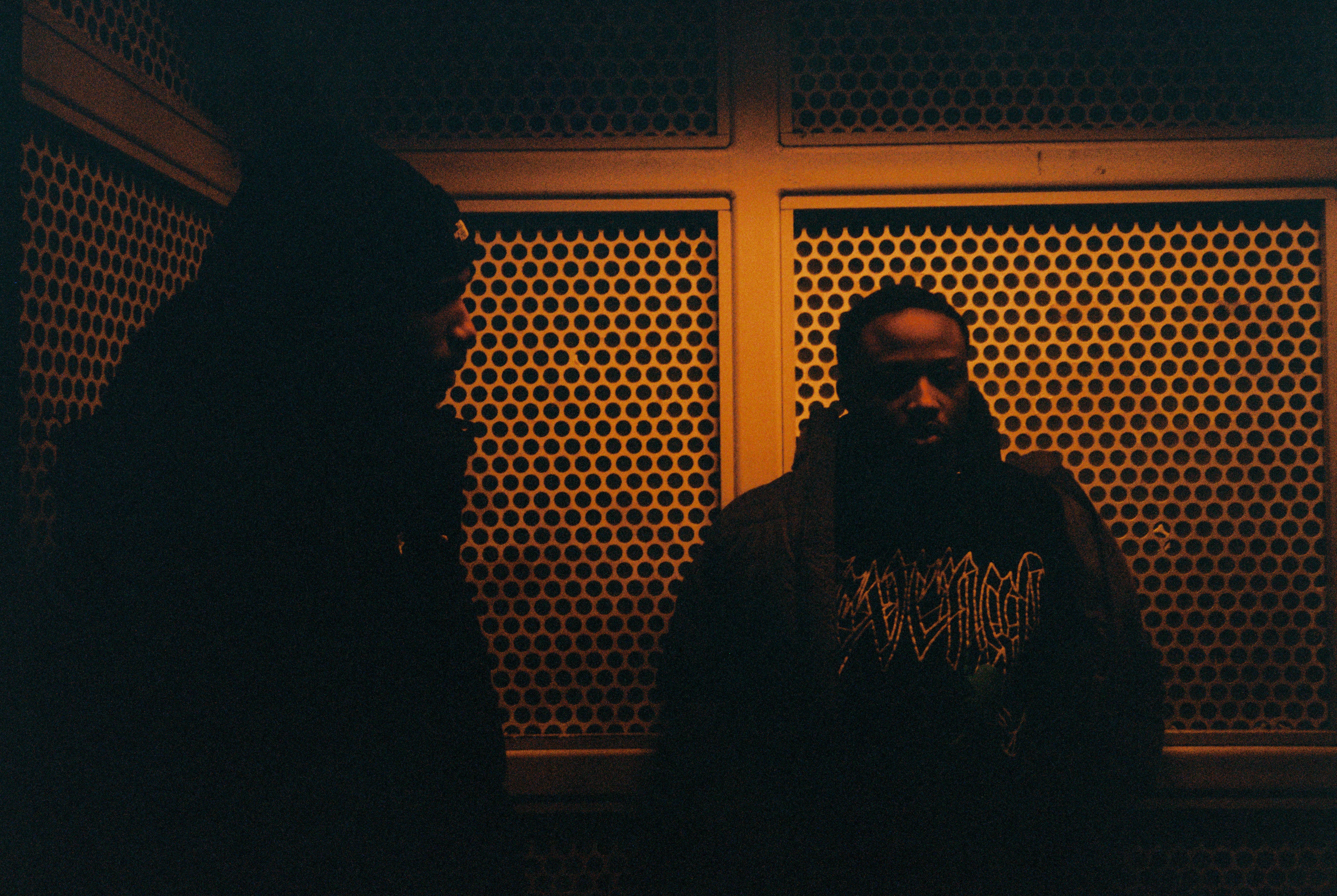 Two men standing in front of a textured wall