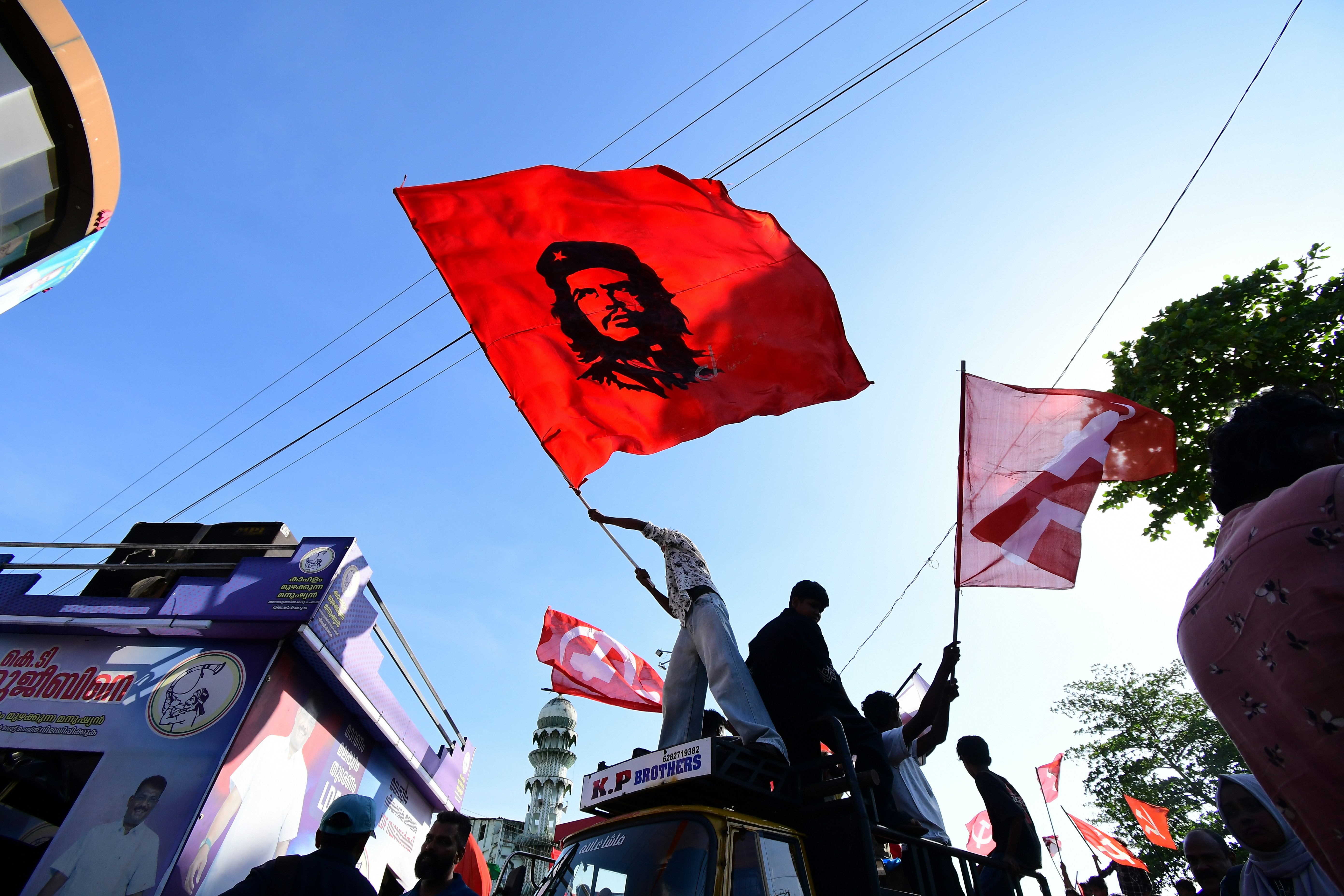 Balaknath giving a fiery speech at a public rally, surrounded by supporters, with party flags in the background.