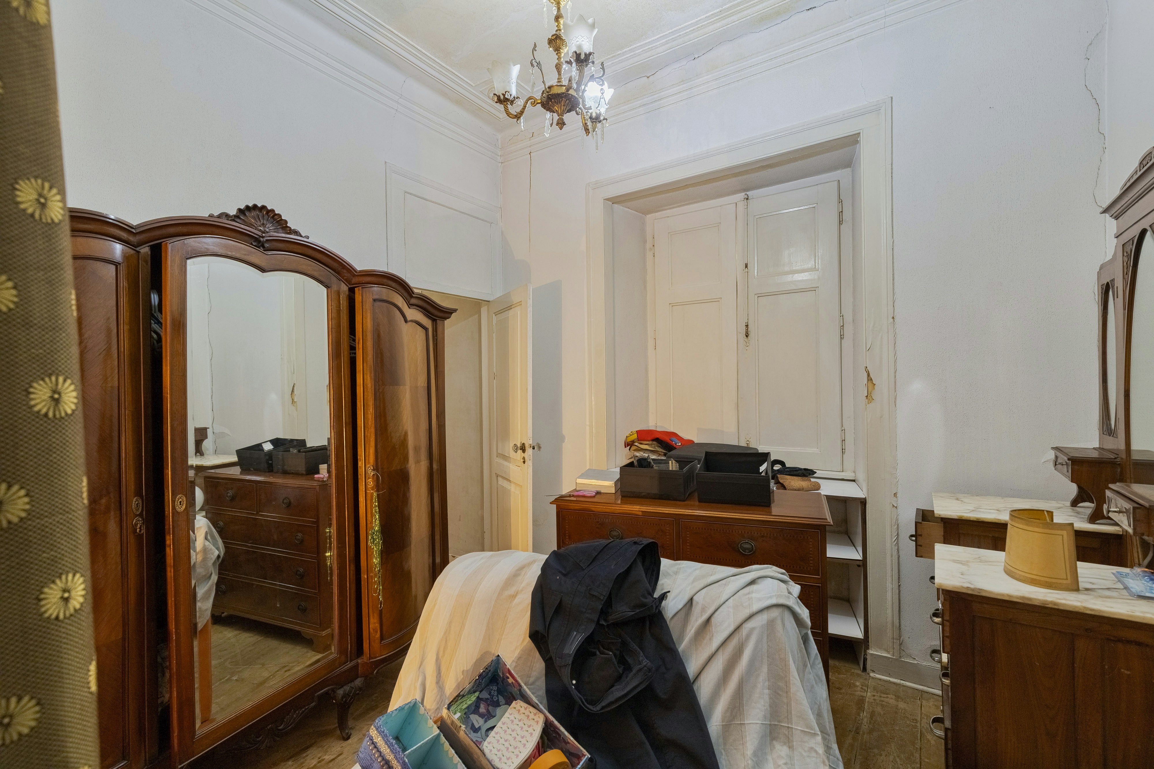 Bedroom with antique wooden furniture and chandelier.