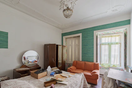 A cluttered bedroom with an orange sofa and vintage furniture