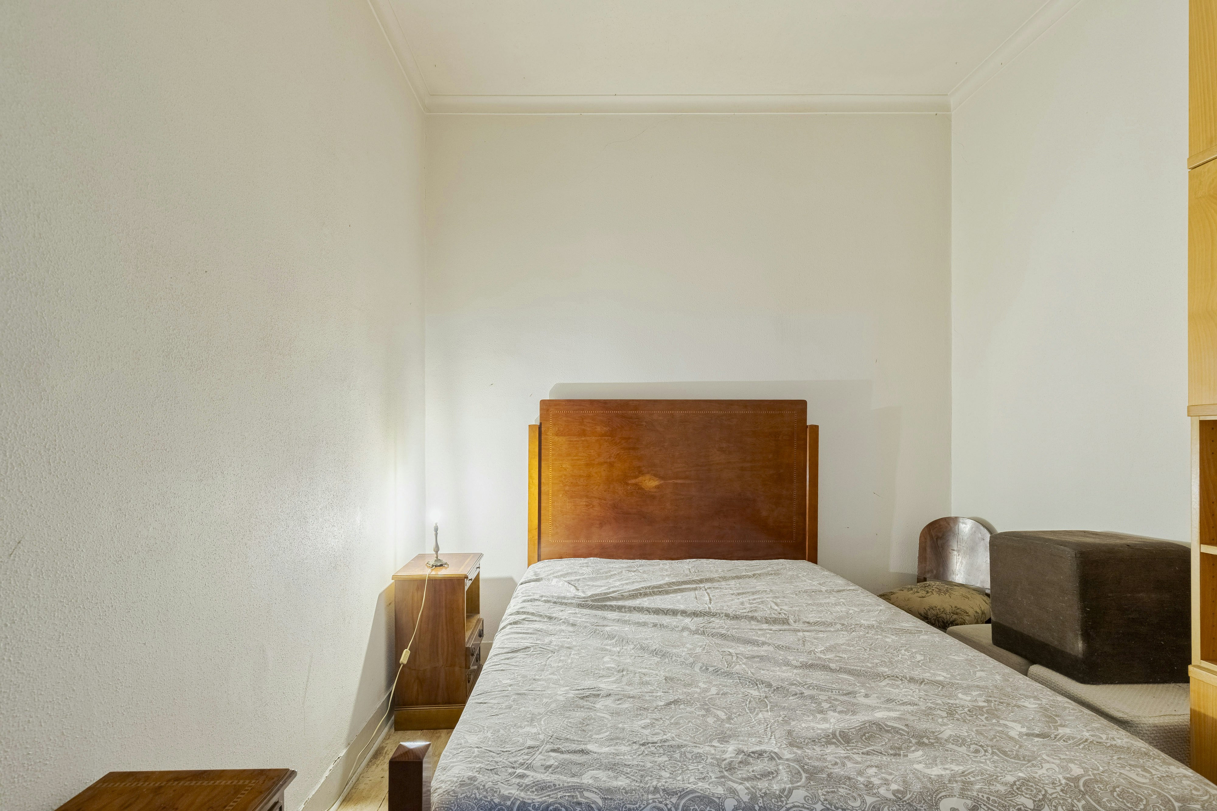 A simple bedroom with a single bed and wooden furniture