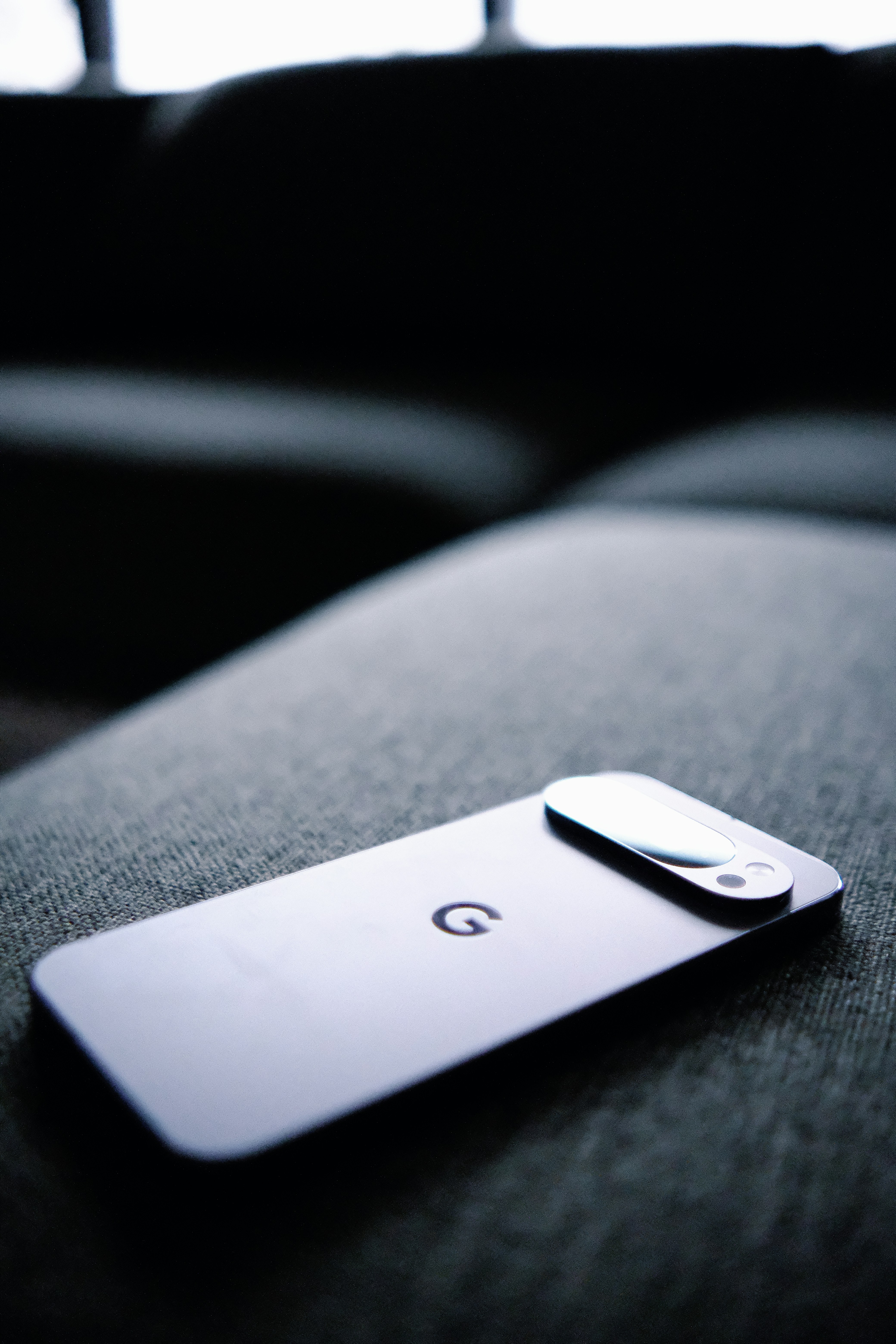 Smartphone dengan logo google bertumpu di sofa.