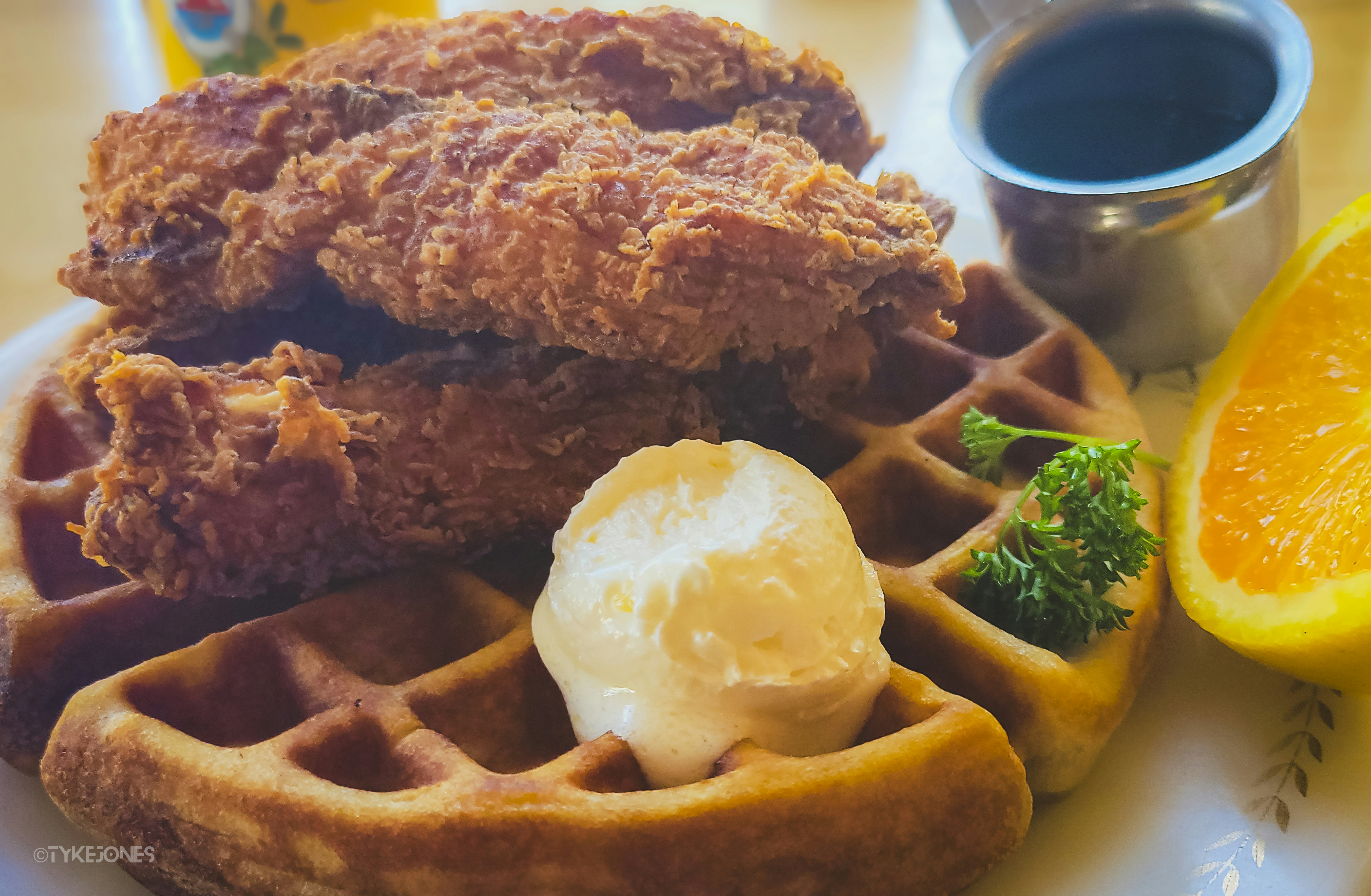 Crispy fried chicken sits atop golden waffles with butter.