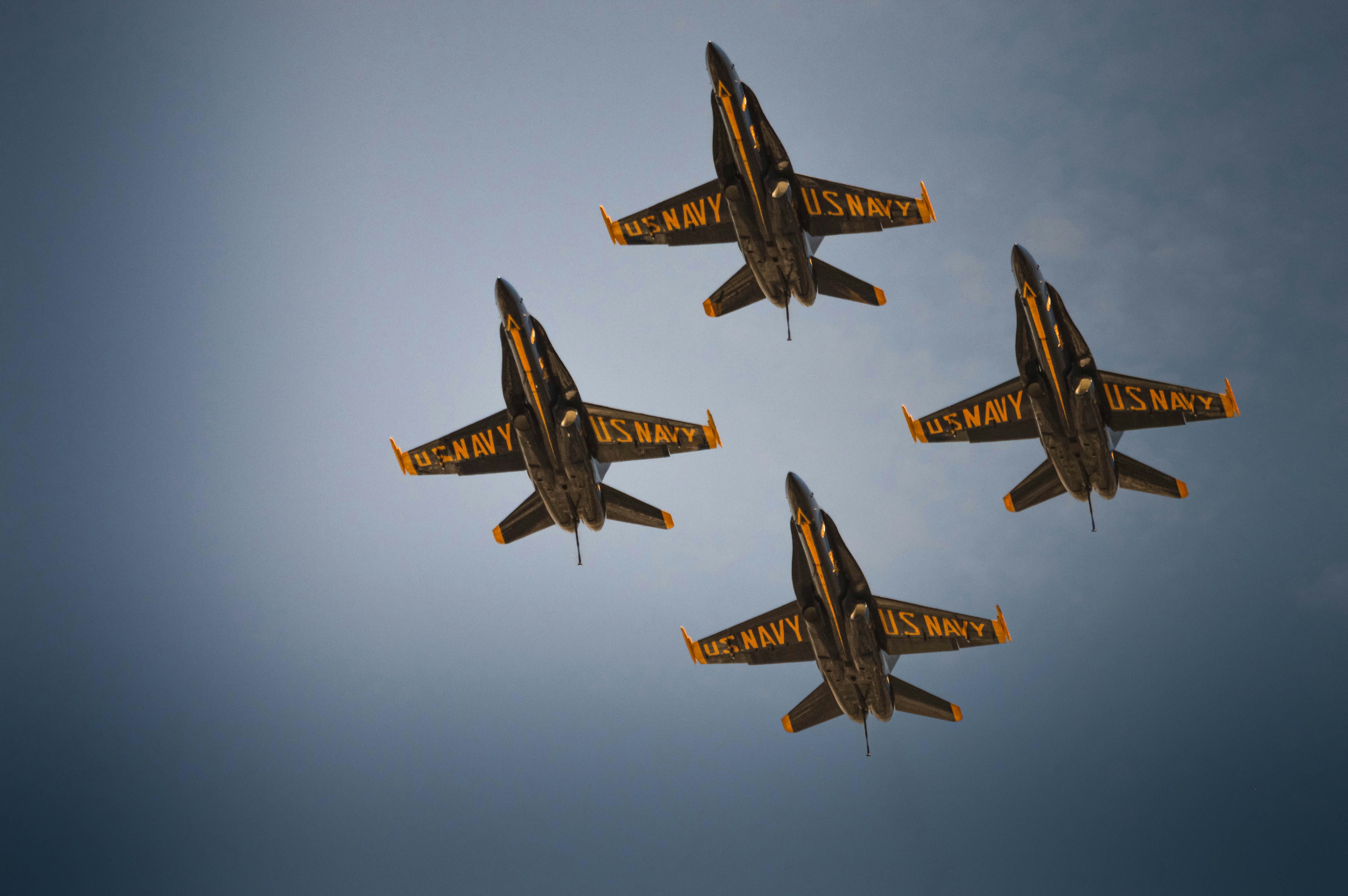 Four navy jets fly in formation against a cloudy sky