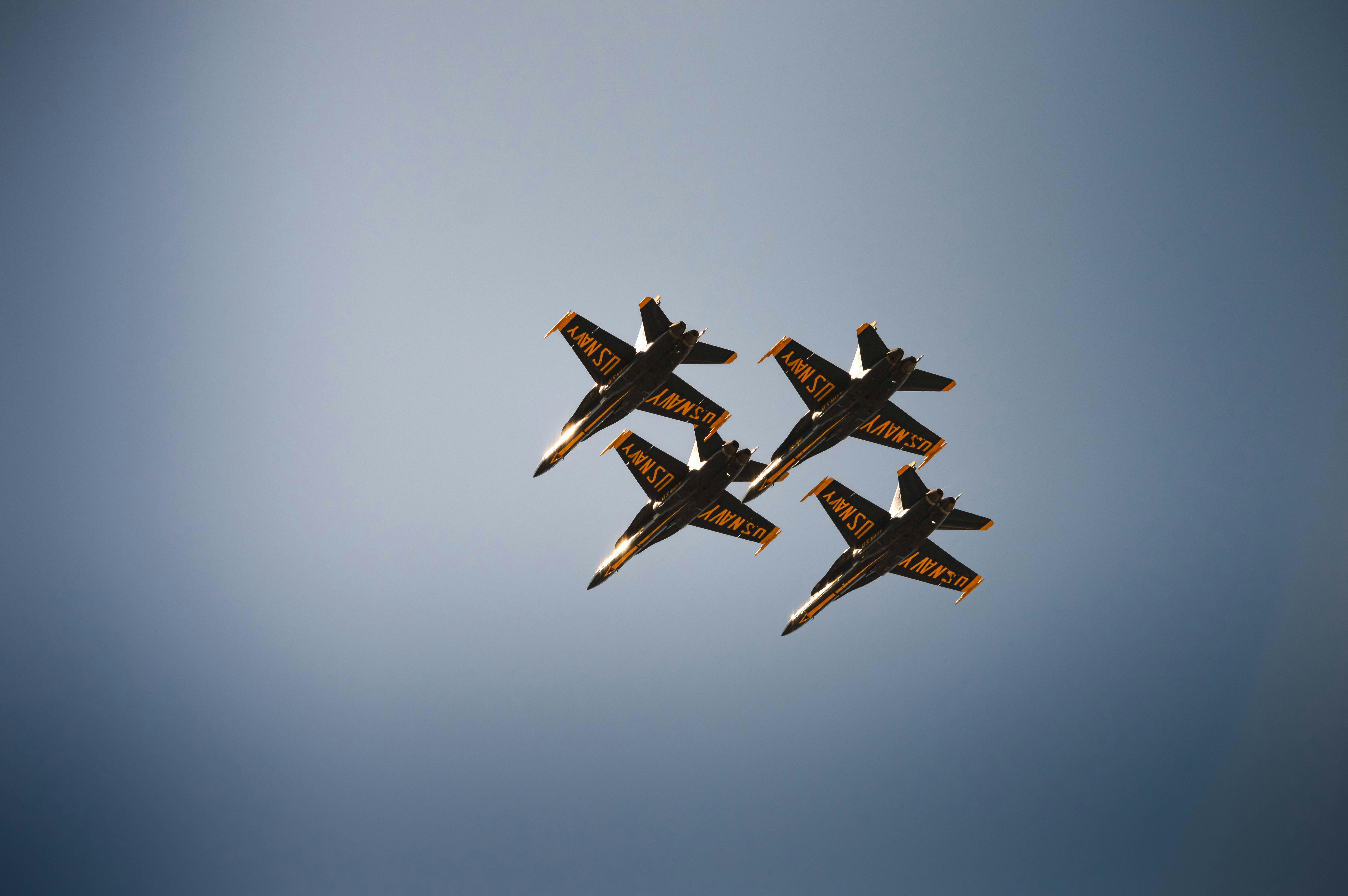 Four fighter jets fly in formation against a blue sky.