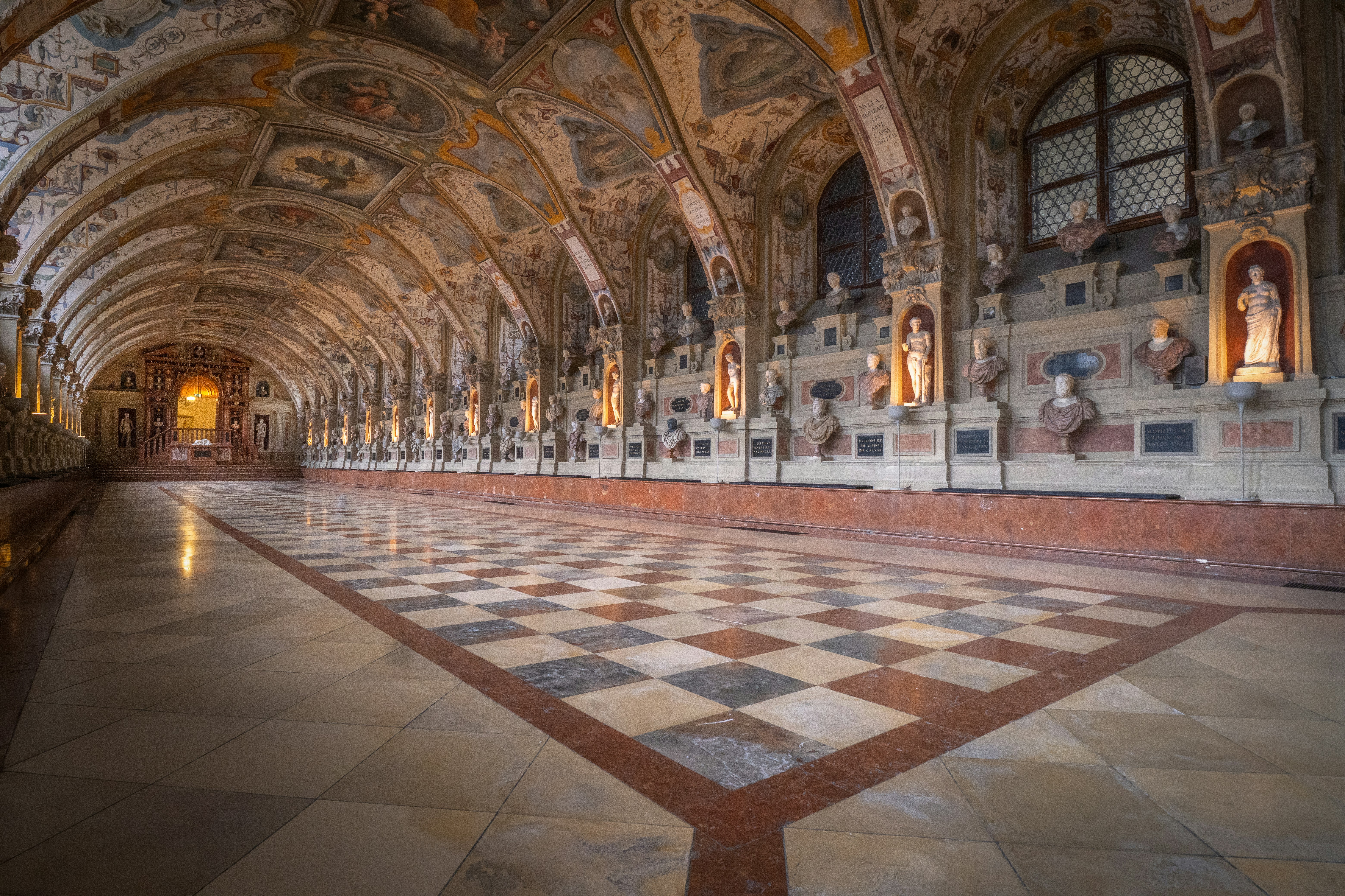Ornate hall with checkered floor and busts along walls