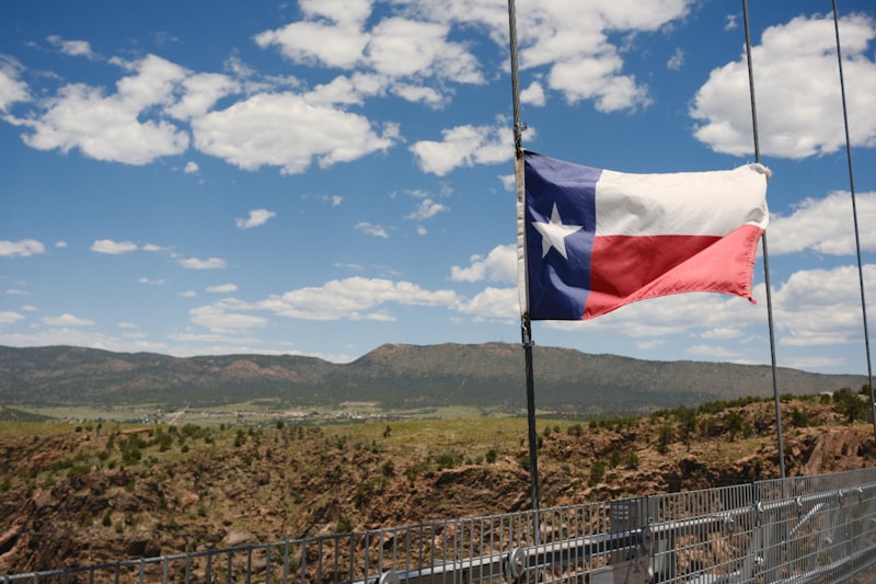 Texas flag waving on a bridge with mountains in the background