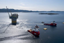 Oil rig platform being towed by support vessels at sea