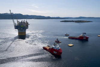 Oil rig platform being towed by support vessels at sea