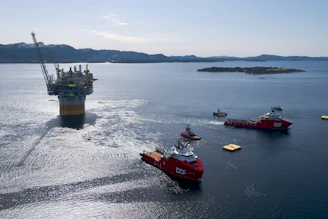 Oil rig platform being towed by support vessels at sea