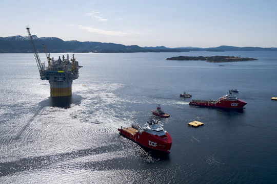 Oil rig platform being towed by support vessels at sea