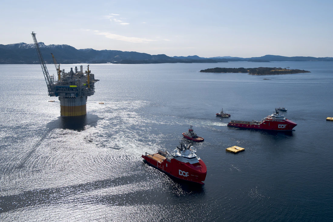 Support vessels towing an offshore platform at sea