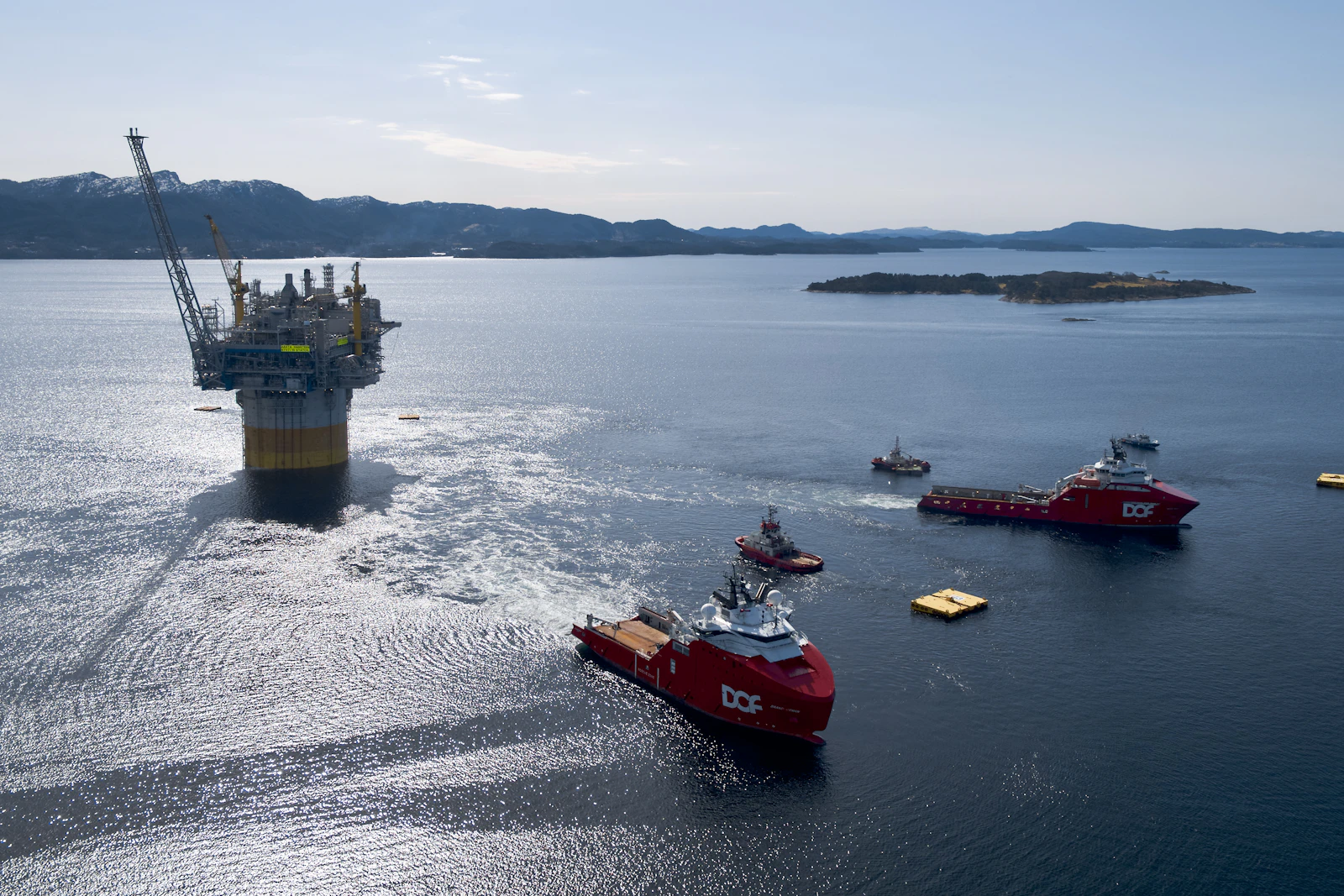 An offshore rig being towed by support vessels at sea