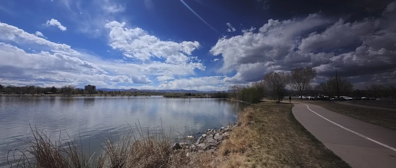 Lake with a paved path and dramatic cloudy sky