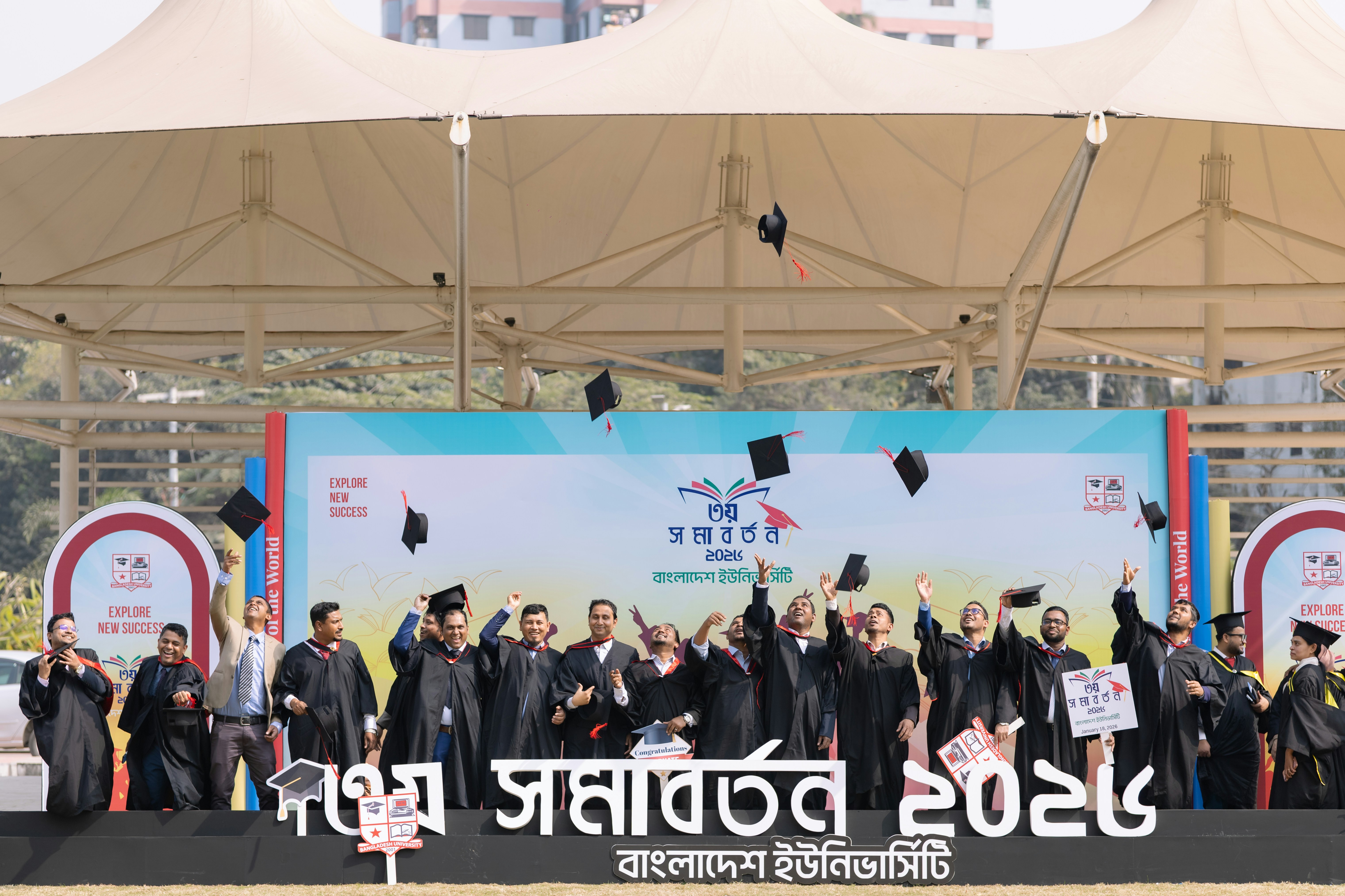 Graduates in caps and gowns toss hats in the air.